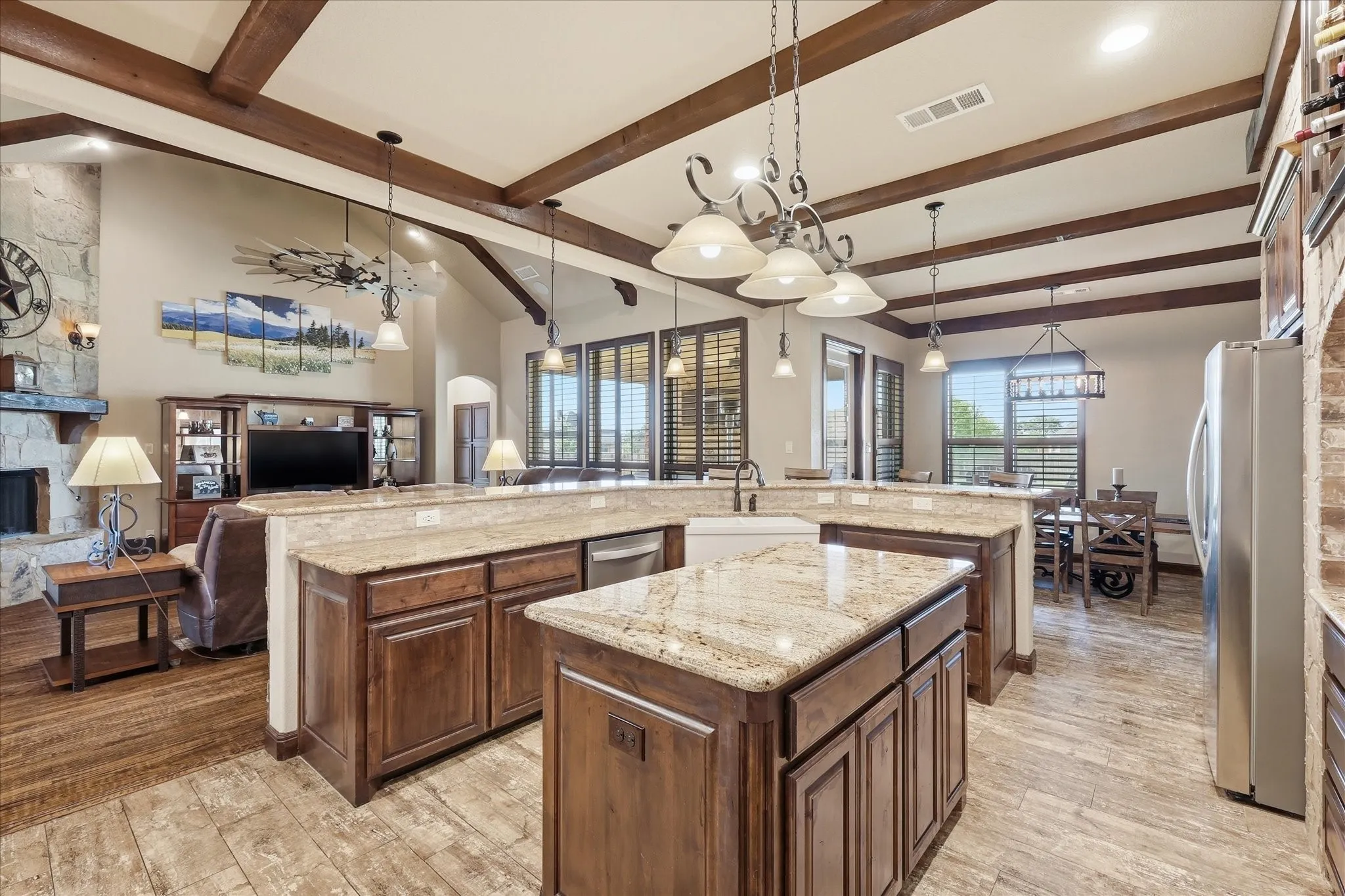 Expansive kitchen featuring a large central island with a farmhouse sink, granite countertops, and rich wood cabinetry