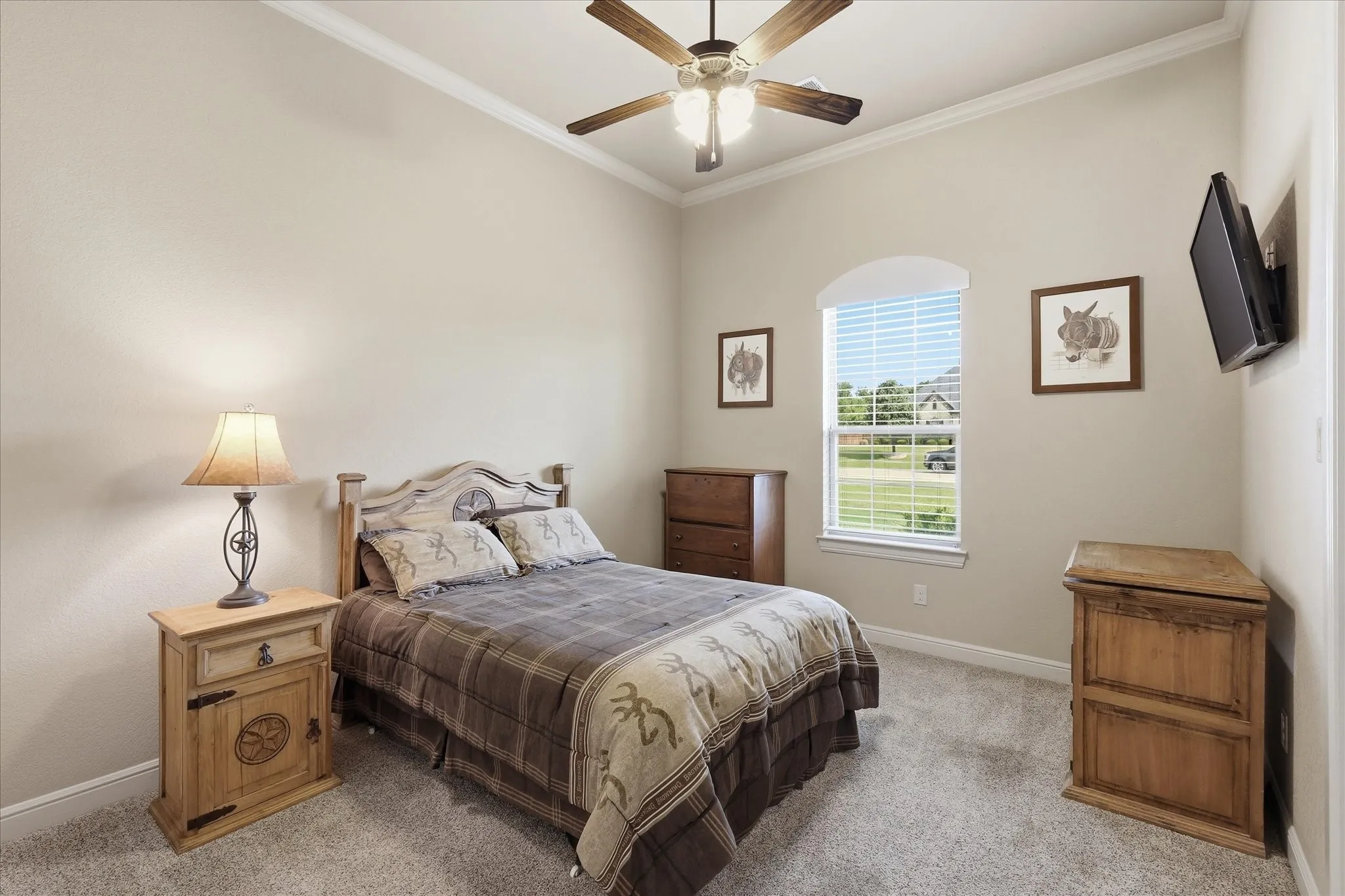Carpeted bedroom featuring neutral wall tones, crown molding, a ceiling fan with light fixture, and an arched window with blinds
