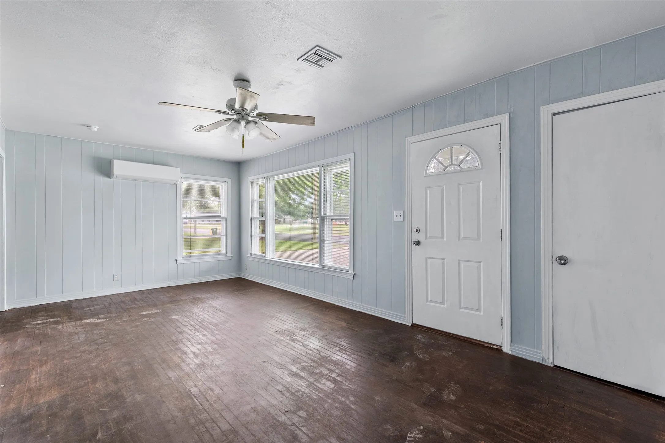 Interior space with wood-finish flooring, light blue panel walls, and multiple windows