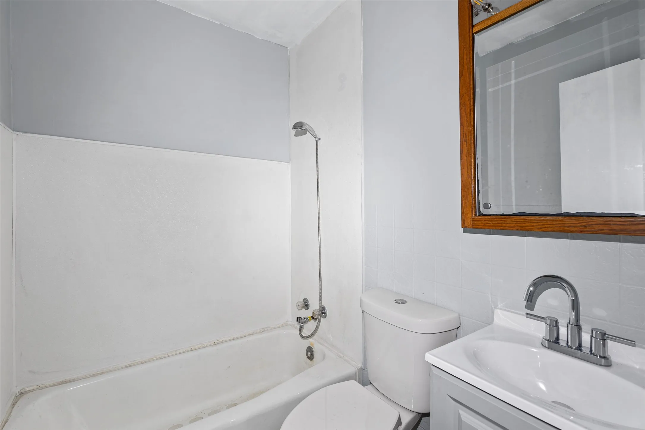 Bathroom featuring a white tub, shower fixture, toilet, and vanity with a white sink