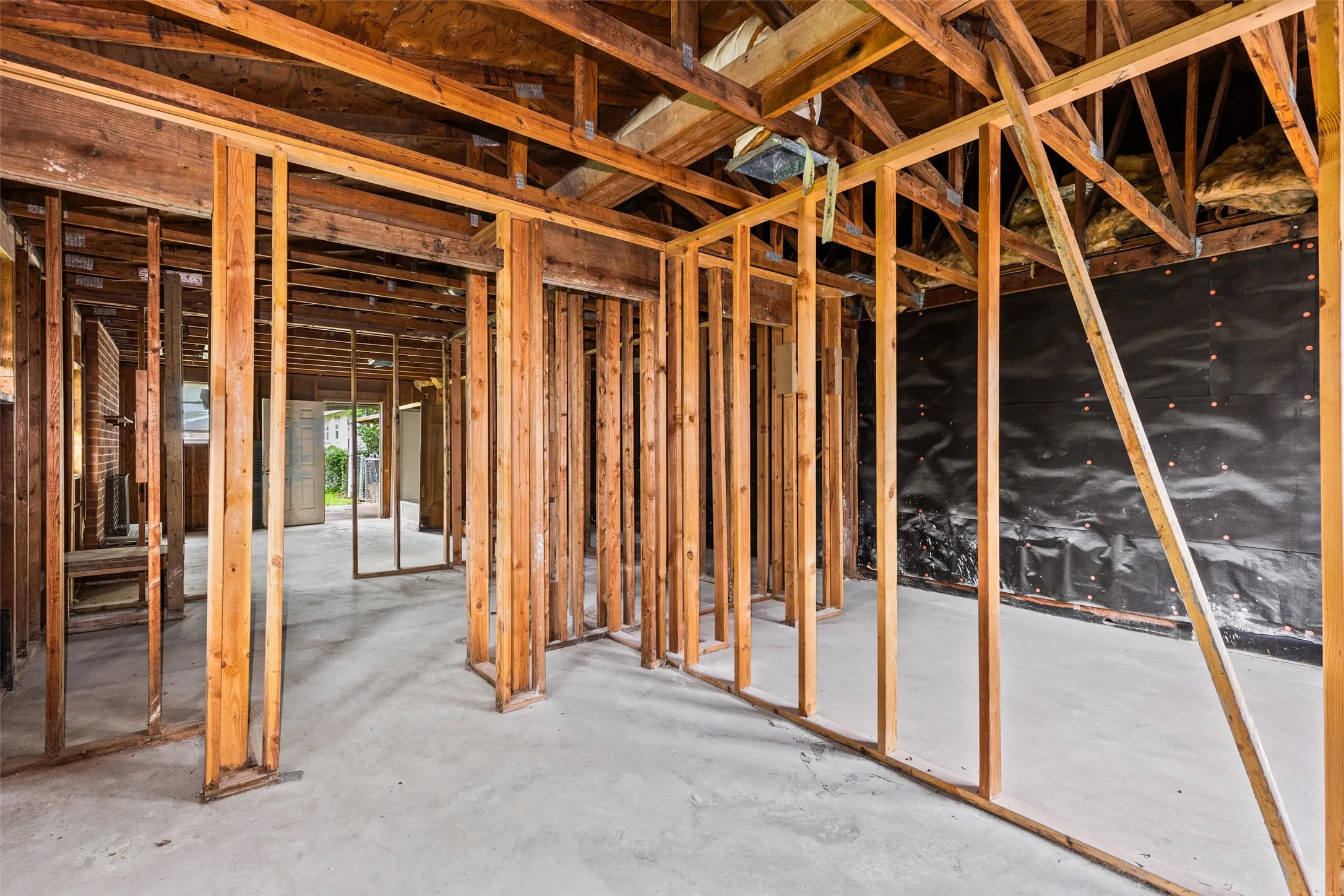 Exposed wooden framing and concrete subfloor define this interior space