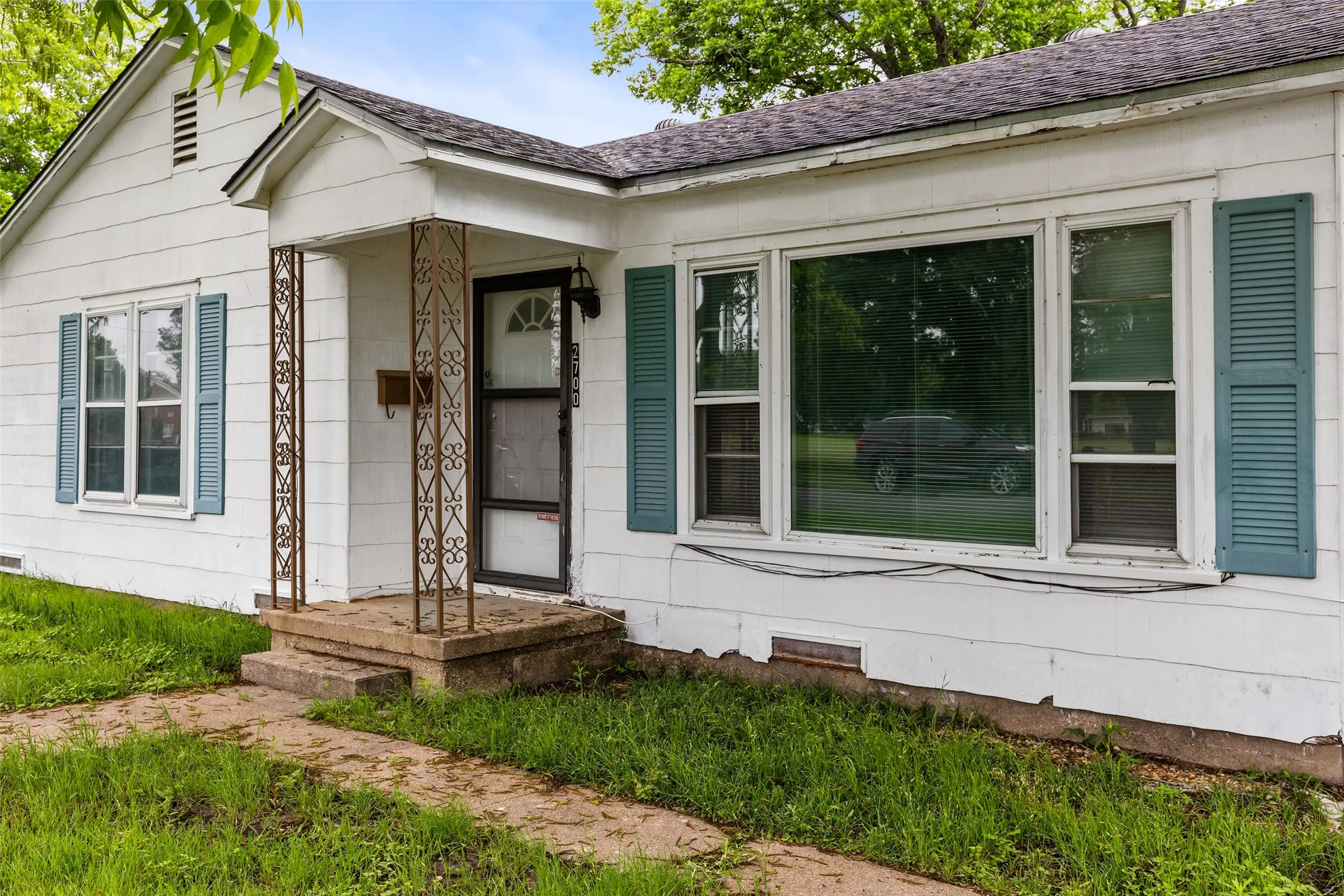 White siding exterior with a front entry porch featuring decorative metal columns