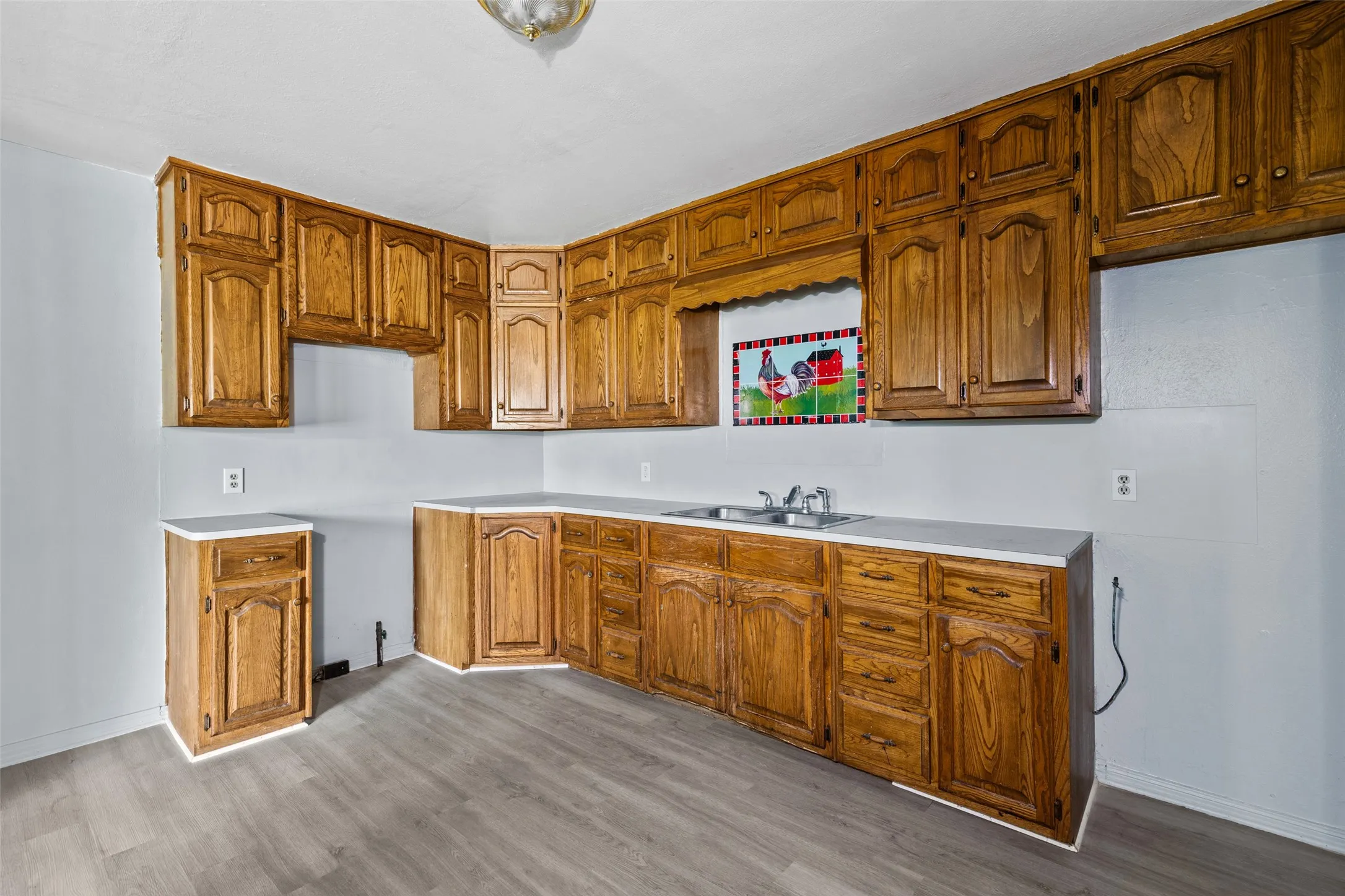 Kitchen featuring extensive wood cabinetry, light-toned countertops, and a double basin stainless steel sink