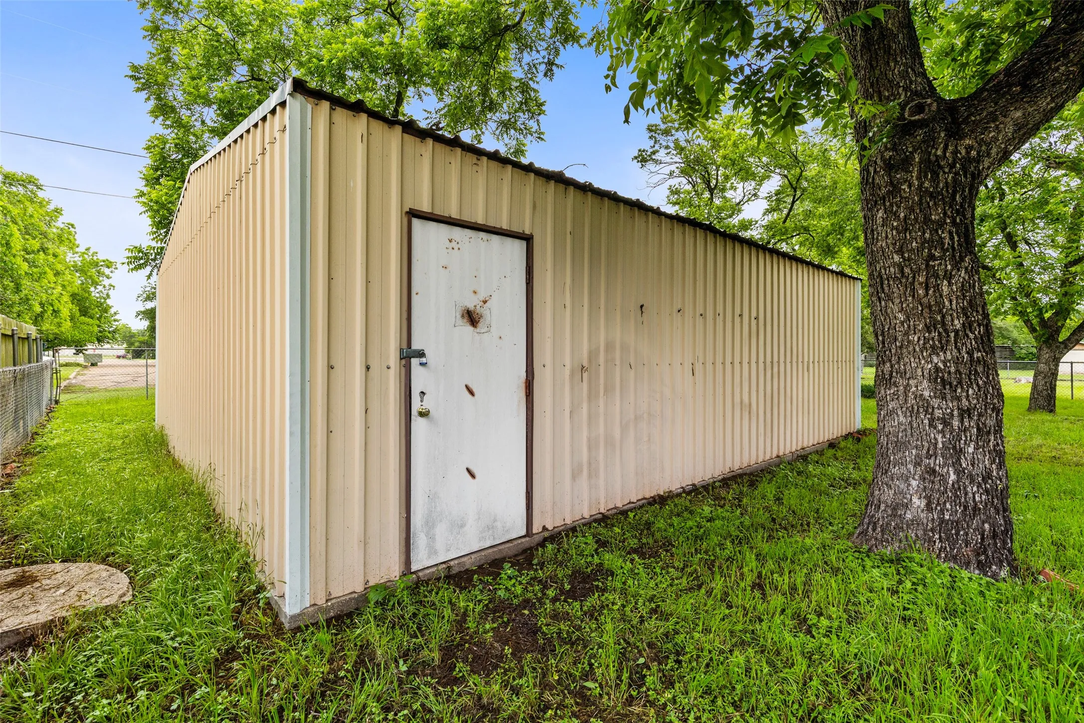 Detached metal outbuilding with a single entry door and corrugated siding