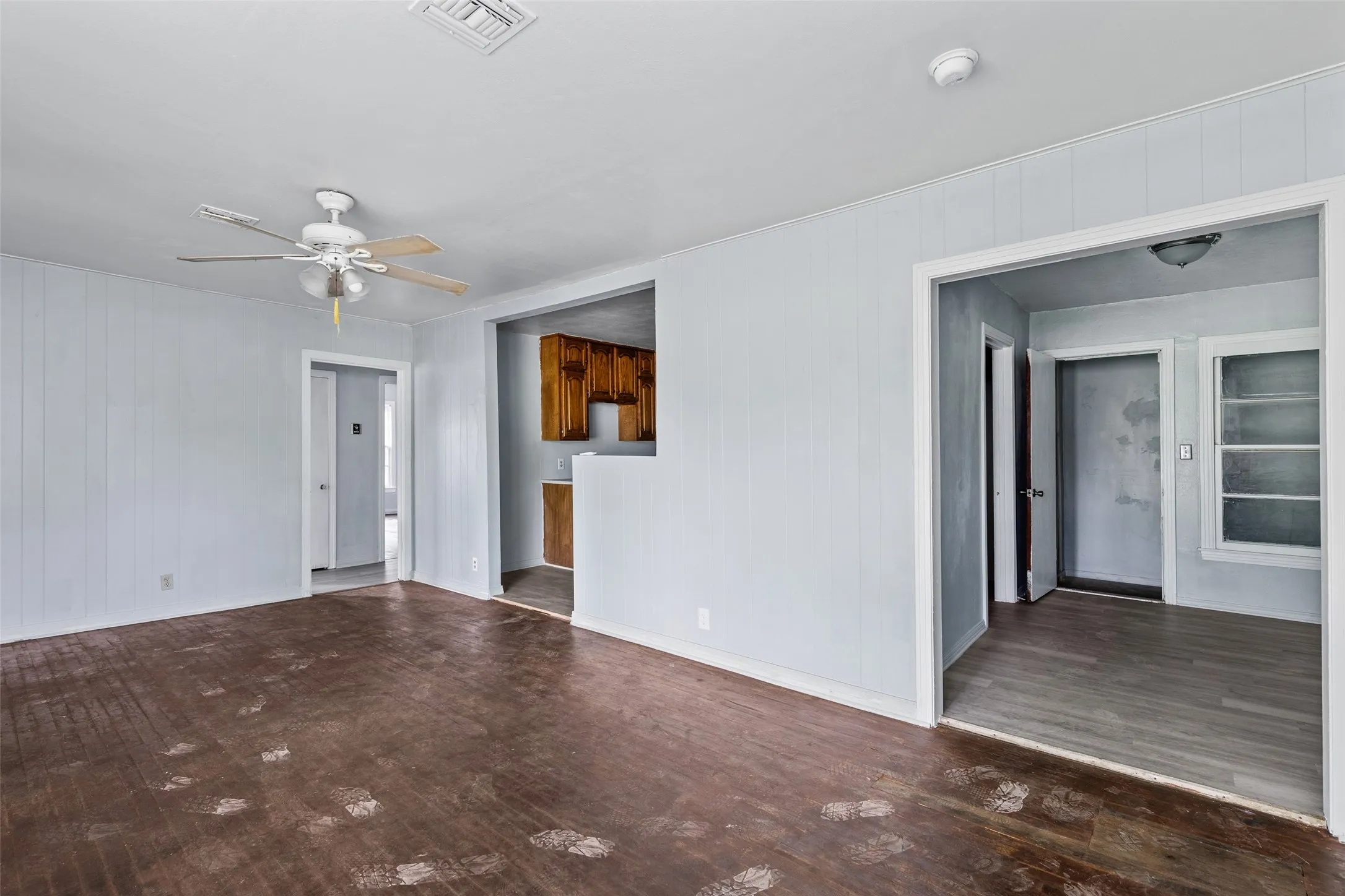 Interior space featuring wood-finish flooring, light-toned wall paneling, and a ceiling fan with integrated lighting