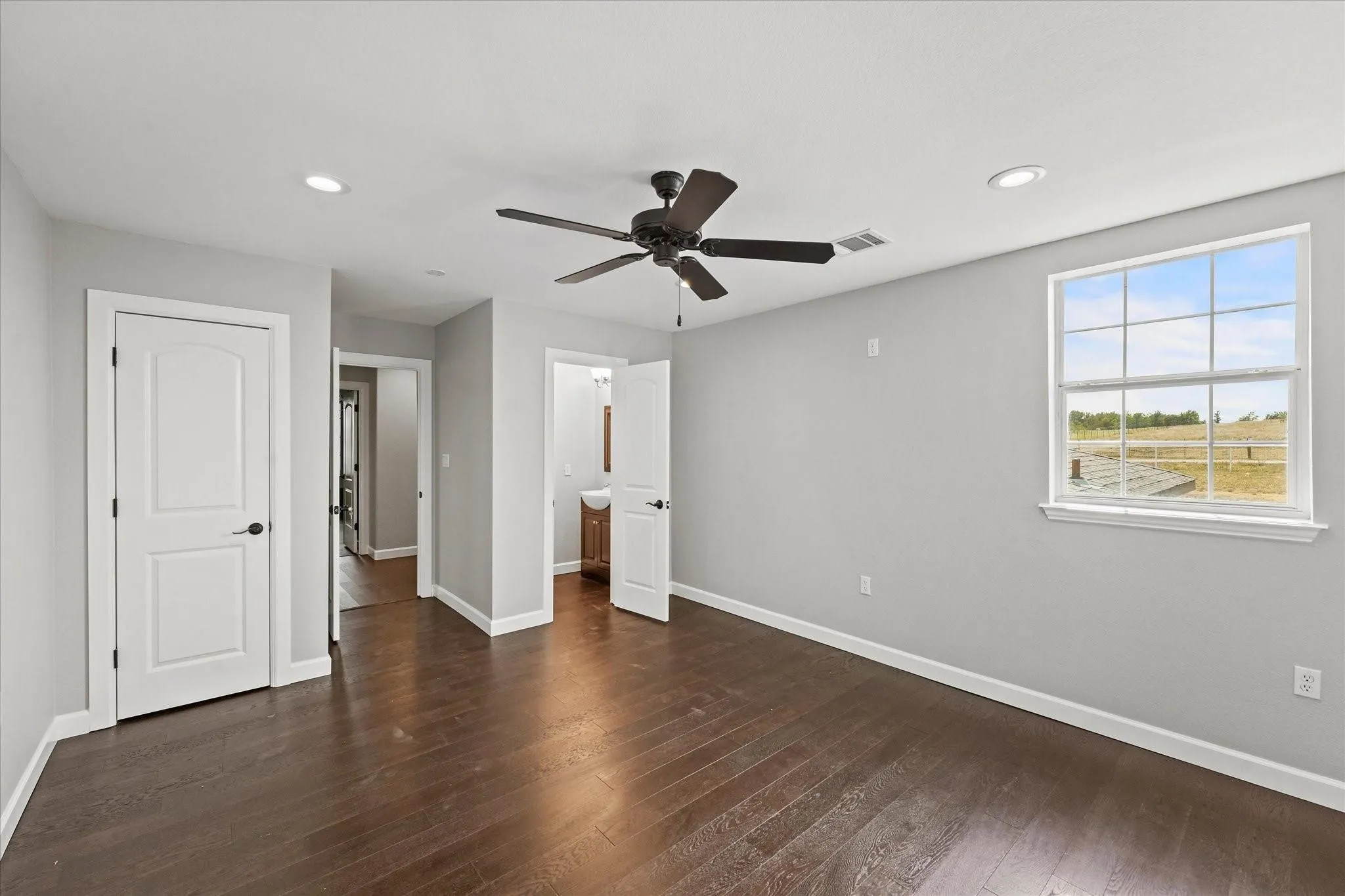Spacious room featuring dark wood-finish flooring, light gray walls, and recessed lighting