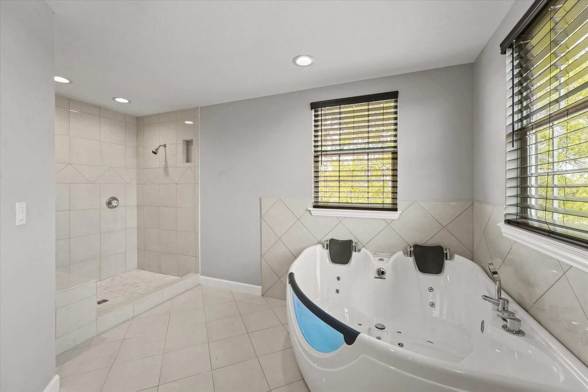 Spacious bathroom featuring a large walk-in shower with tiled walls, a built-in shower niche, and a corner jetted bathtub