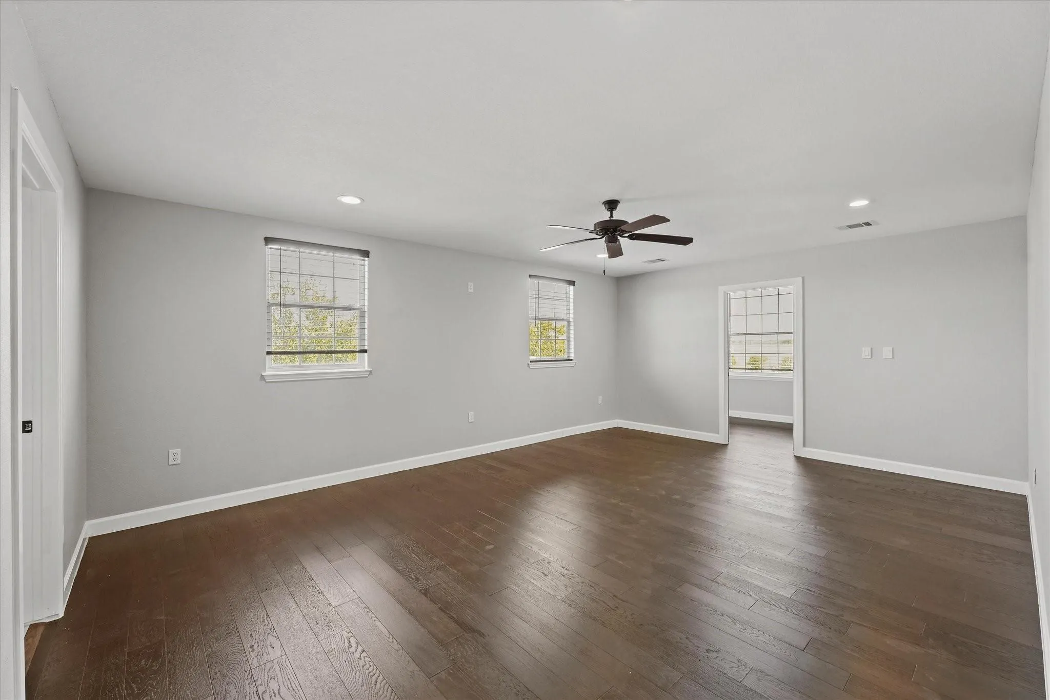 Spacious room featuring rich wood-finish flooring, light gray walls, and white trim