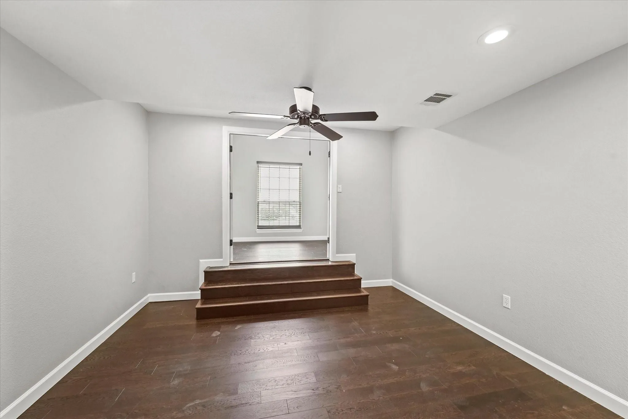 Room featuring dark wood-finish flooring, light grey painted walls, and white baseboards