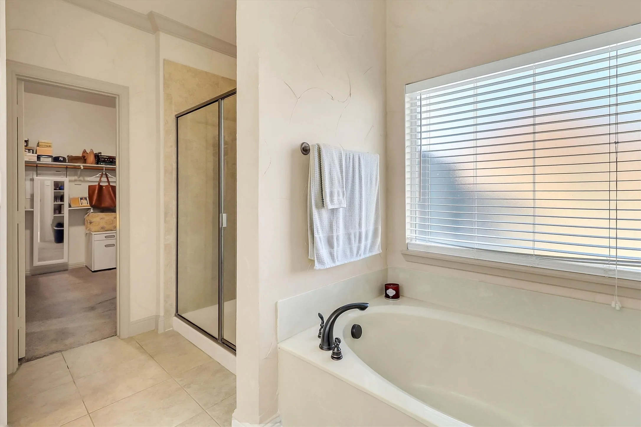 Deep soaking tub with dark bronze fixtures and window blinds for privacy