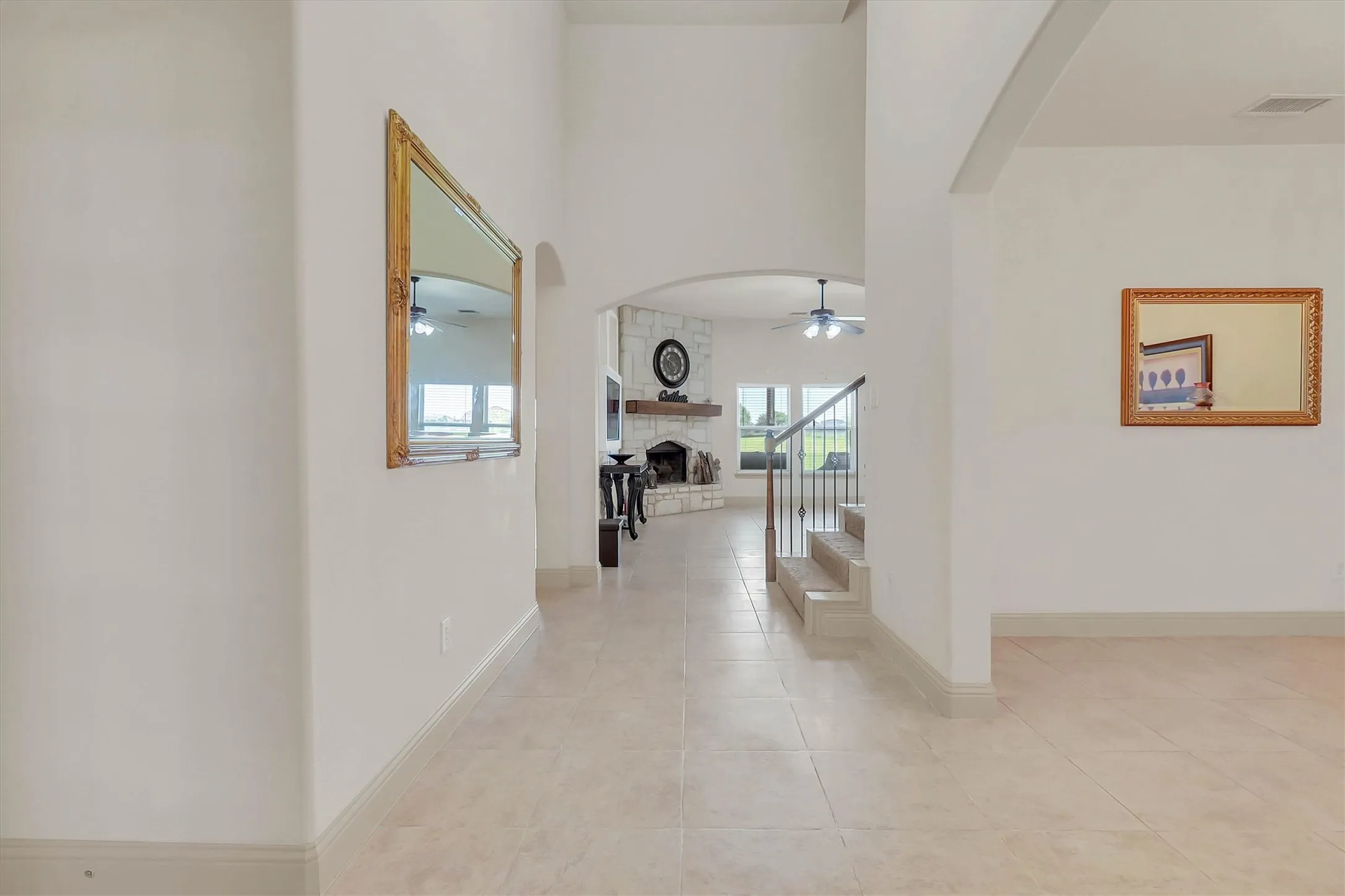 Foyer featuring tile flooring, archway entry, and a stone-clad fireplace with a wood mantle
