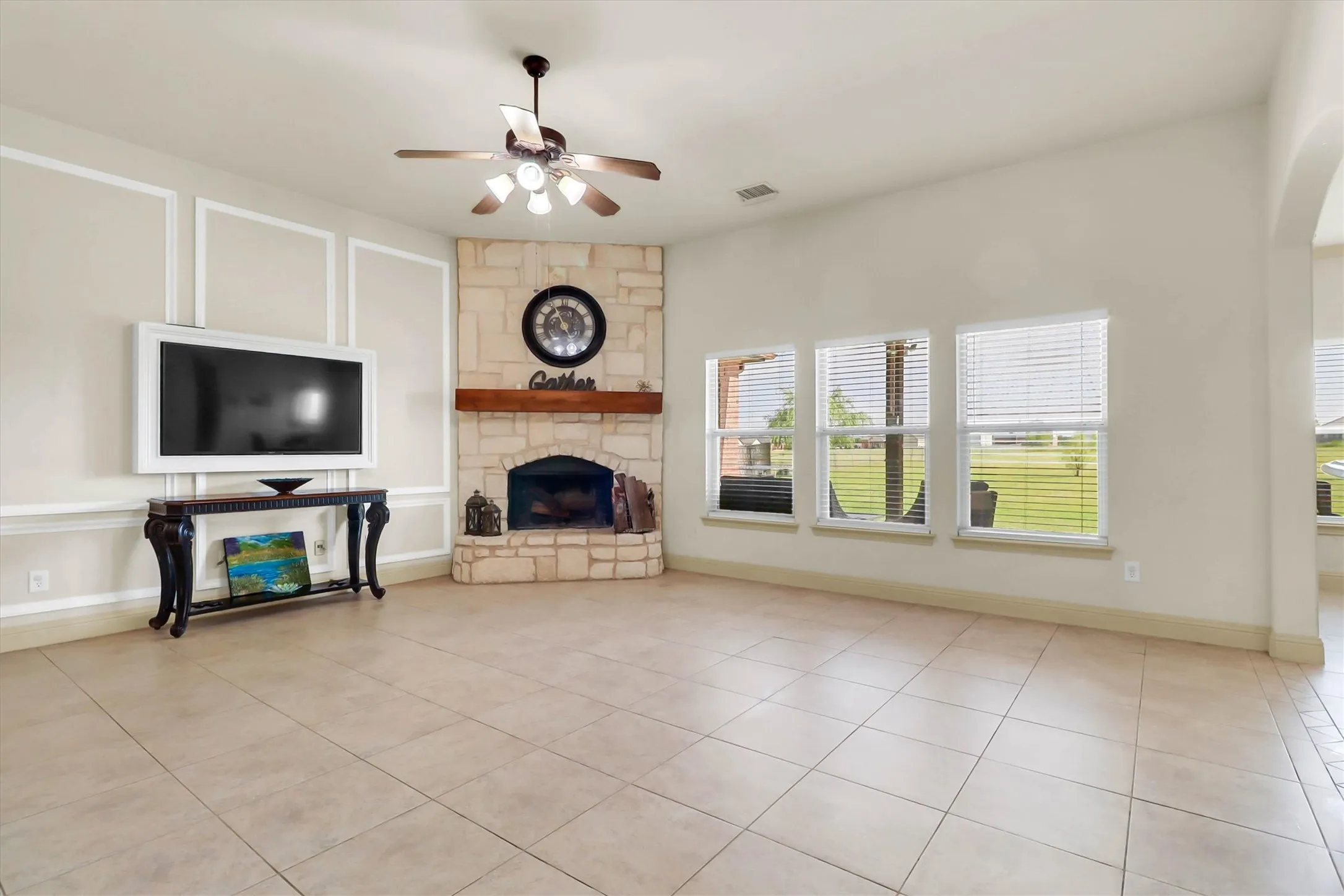 Living area with ceramic tile flooring, a stone fireplace with wood mantel, and multiple windows