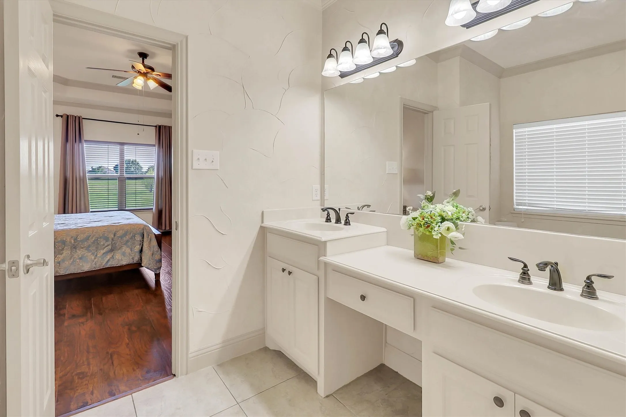 Bathroom featuring a dual vanity with white countertops, integrated sinks, dark bronze fixtures, and a dressing table area