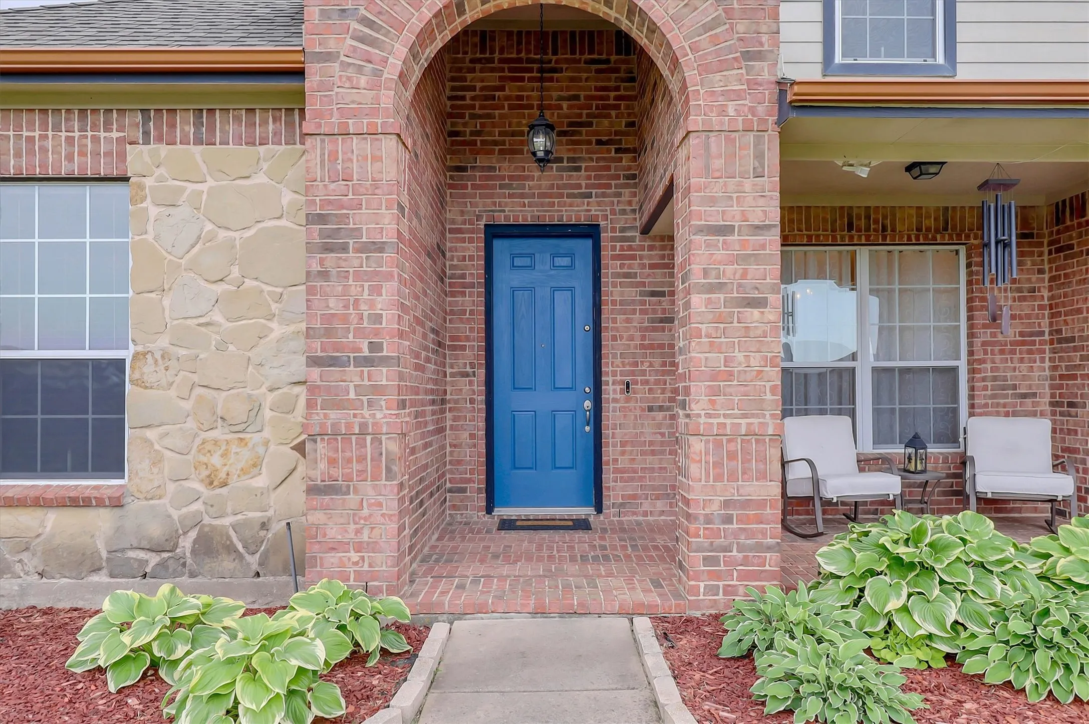 Brick and stone exterior featuring an arched entryway leading to a vibrant blue paneled door