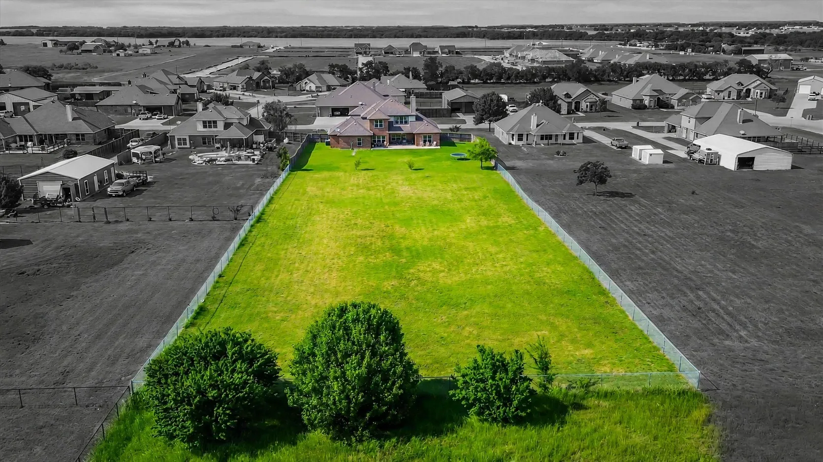 Spacious residential lot featuring a verdant lawn, established trees, and perimeter fencing