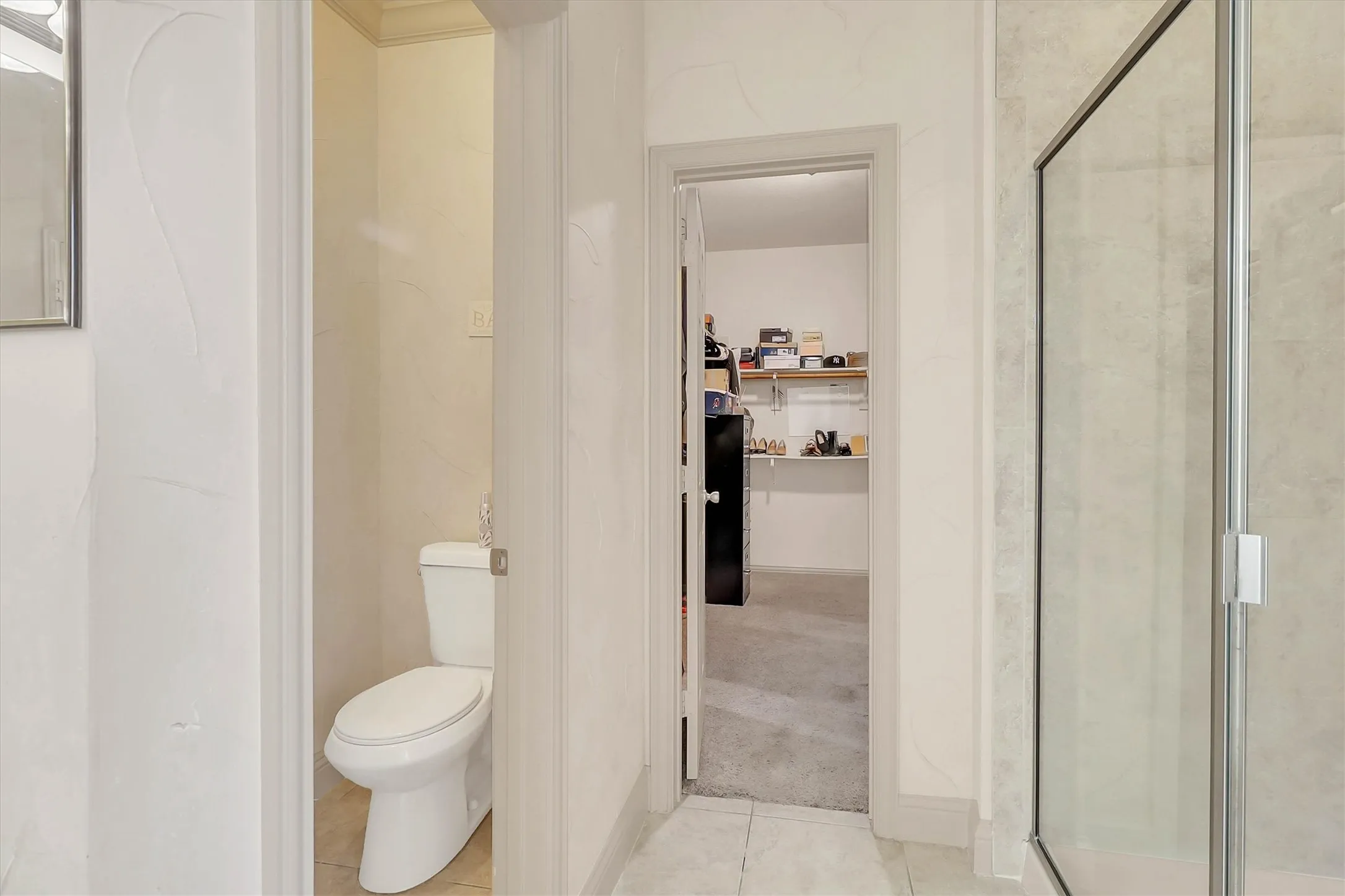Bathroom featuring a walk-in shower with clear glass enclosure and light-toned tile surround
