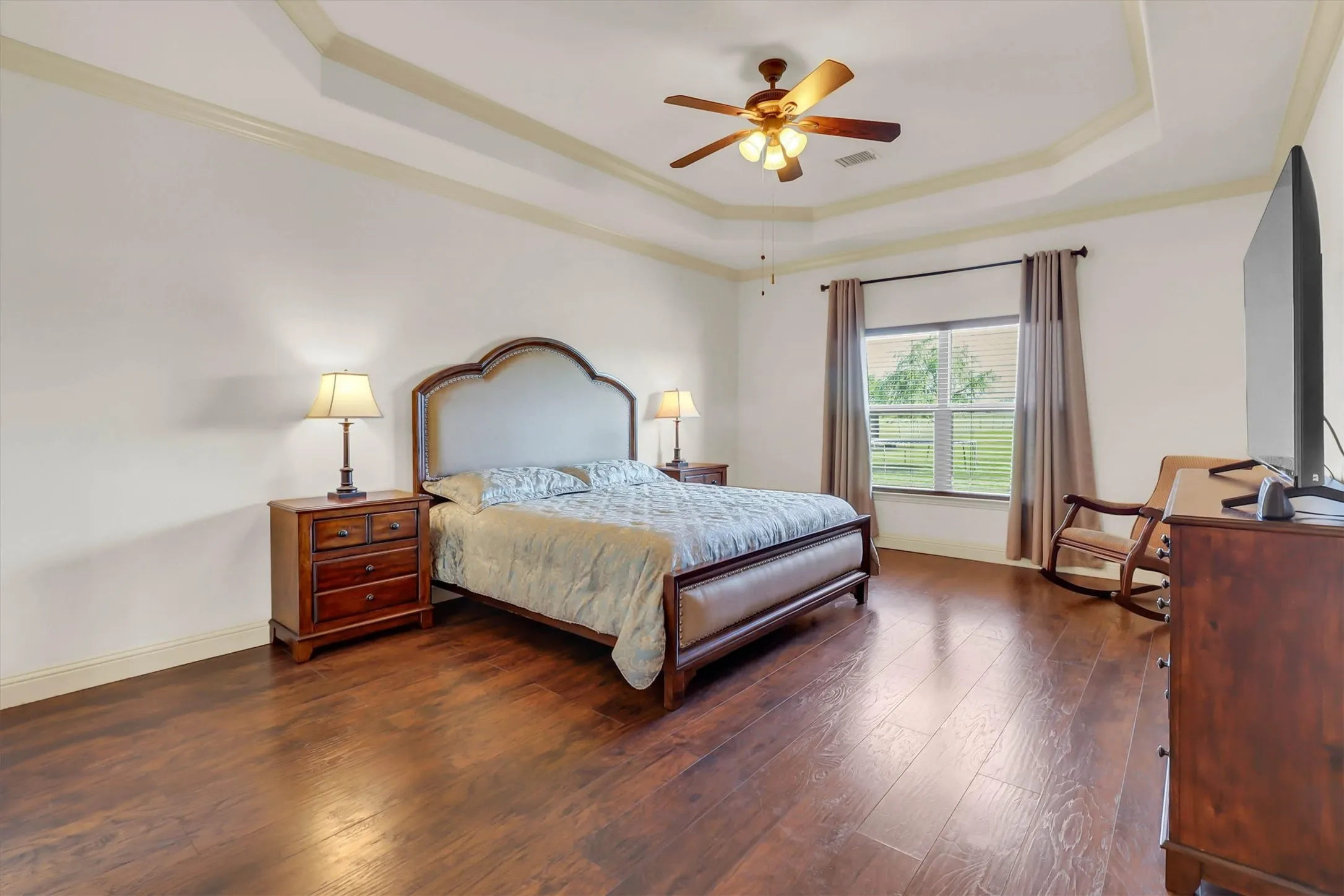 Spacious interior featuring wood-finish flooring, a tray ceiling, and a ceiling fan with integrated lighting