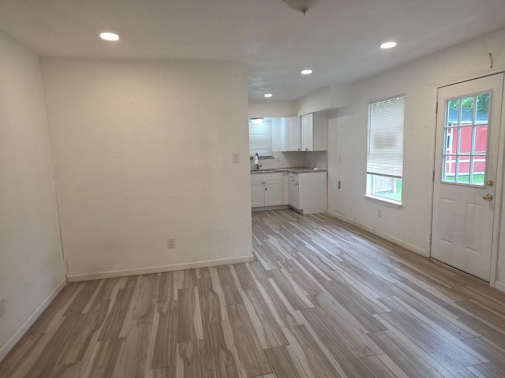 Spacious open-concept area featuring wood-finish flooring, white walls, and recessed lighting