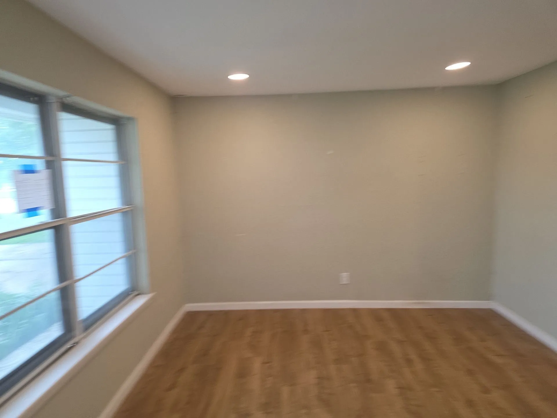 Room featuring wood-finish flooring, recessed ceiling lighting, and a large multi-pane window