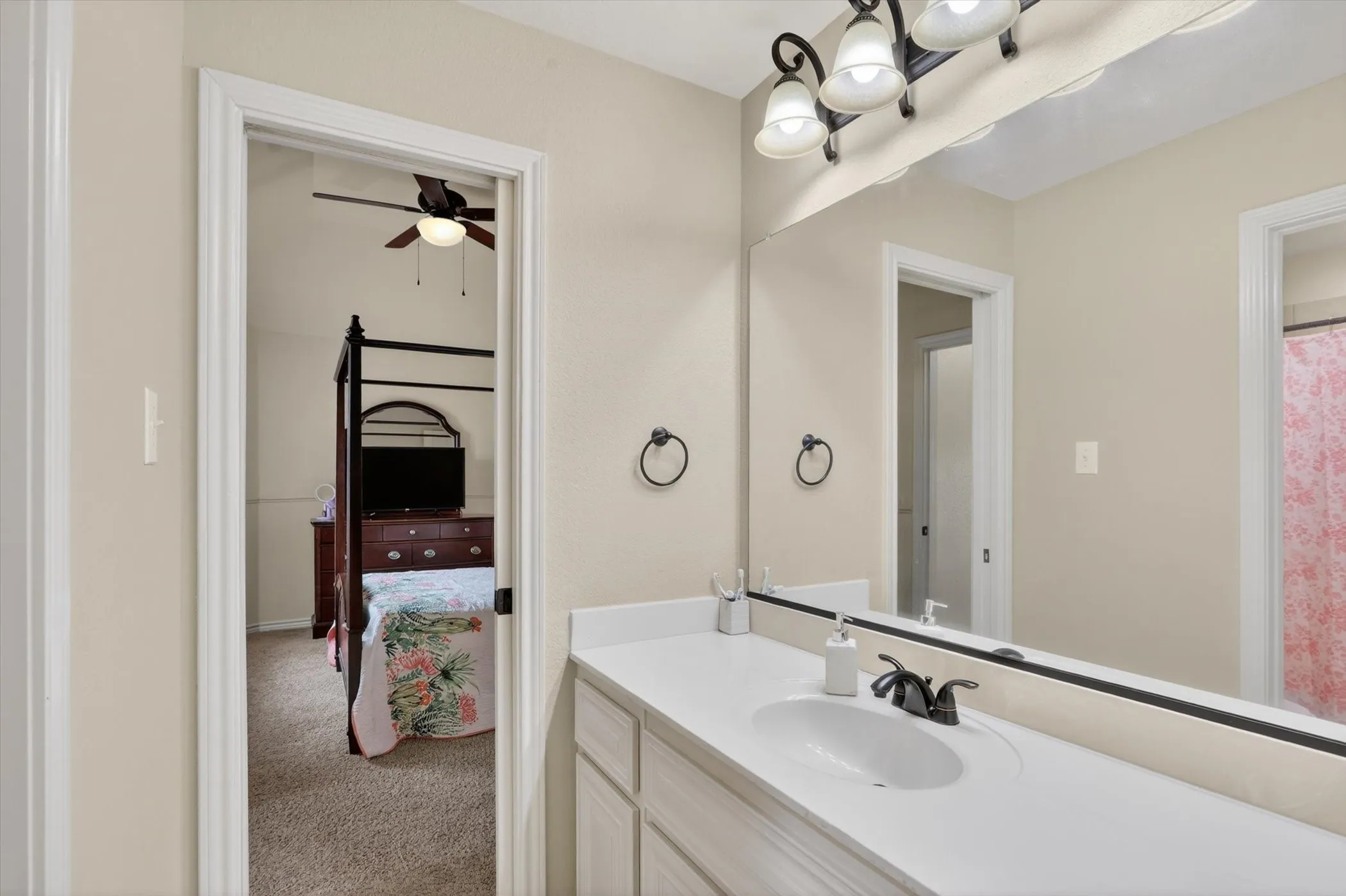 Vanity with an integrated sink, dark bronze faucet, and a large wall-mounted mirror