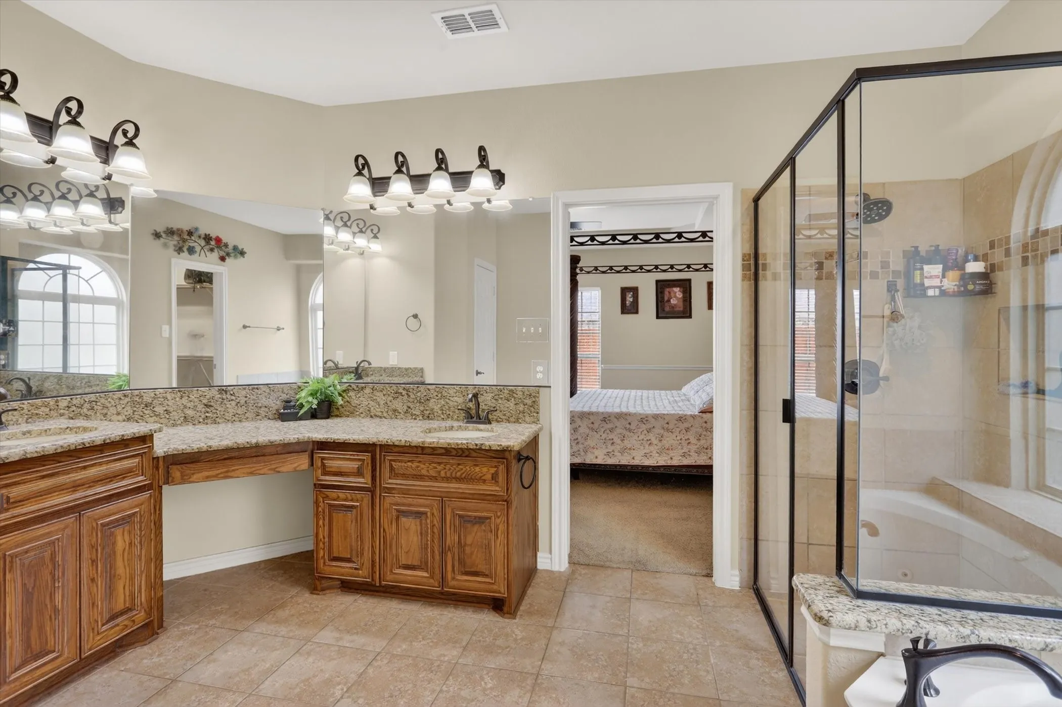 Primary bathroom featuring dual vanities with granite countertops, wood cabinetry, and integrated sinks