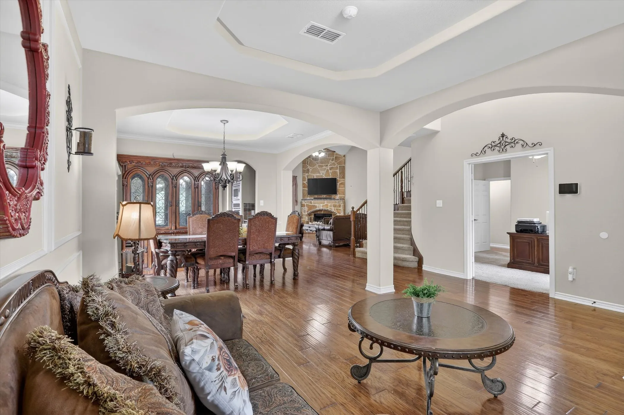 Open concept interior featuring wood-finish flooring, arched doorways, and tray ceilings