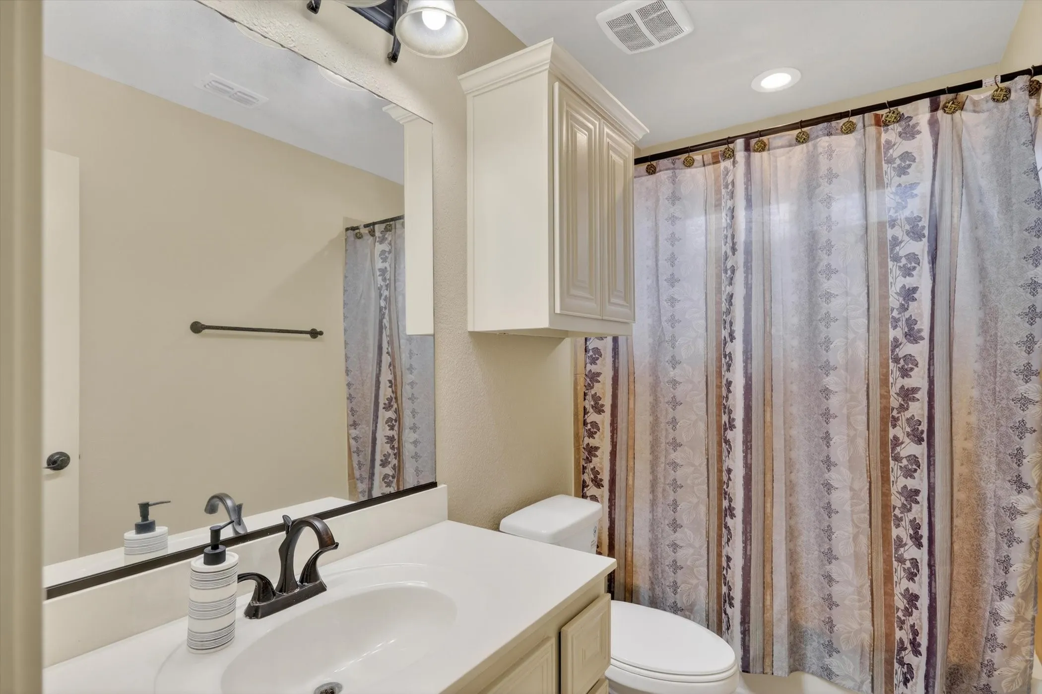 Bathroom vanity with an integrated sink, bronze-finish faucet, and coordinating overhead lighting upstairs