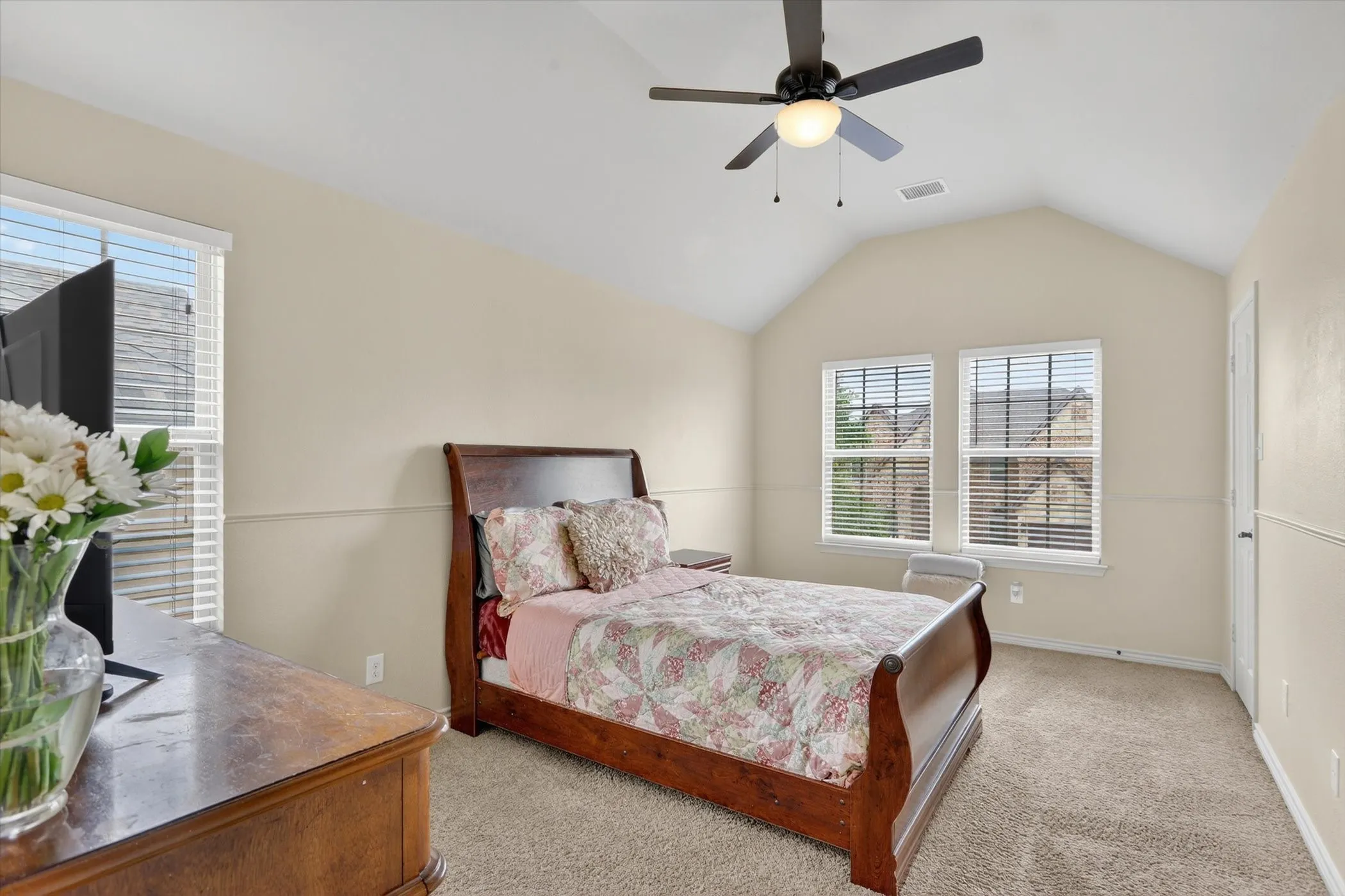 Vaulted ceiling bedroom with neutral wall tones and textured carpeting