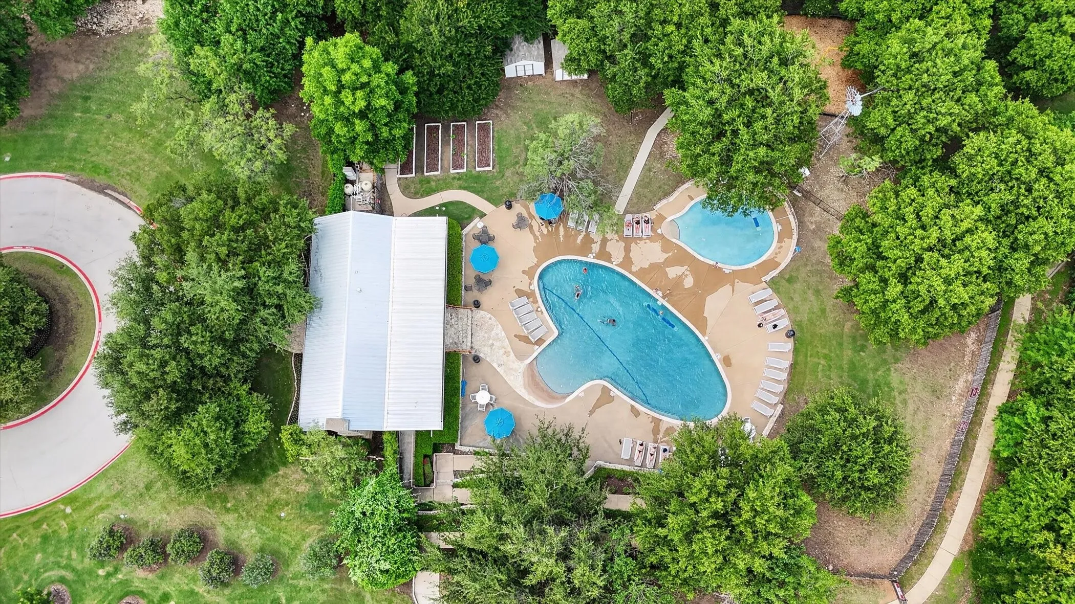 Expansive outdoor recreation area featuringl swimming pool with integrated tanning ledge, paved patio decking, and mature landscaping, plus a walking trail around Marine Creek Lake
