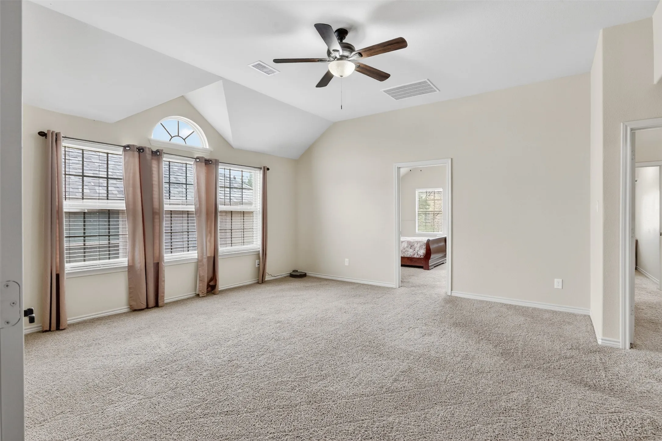 Vaulted ceiling with a ceiling fan, arched transom window, and multiple windows with blinds