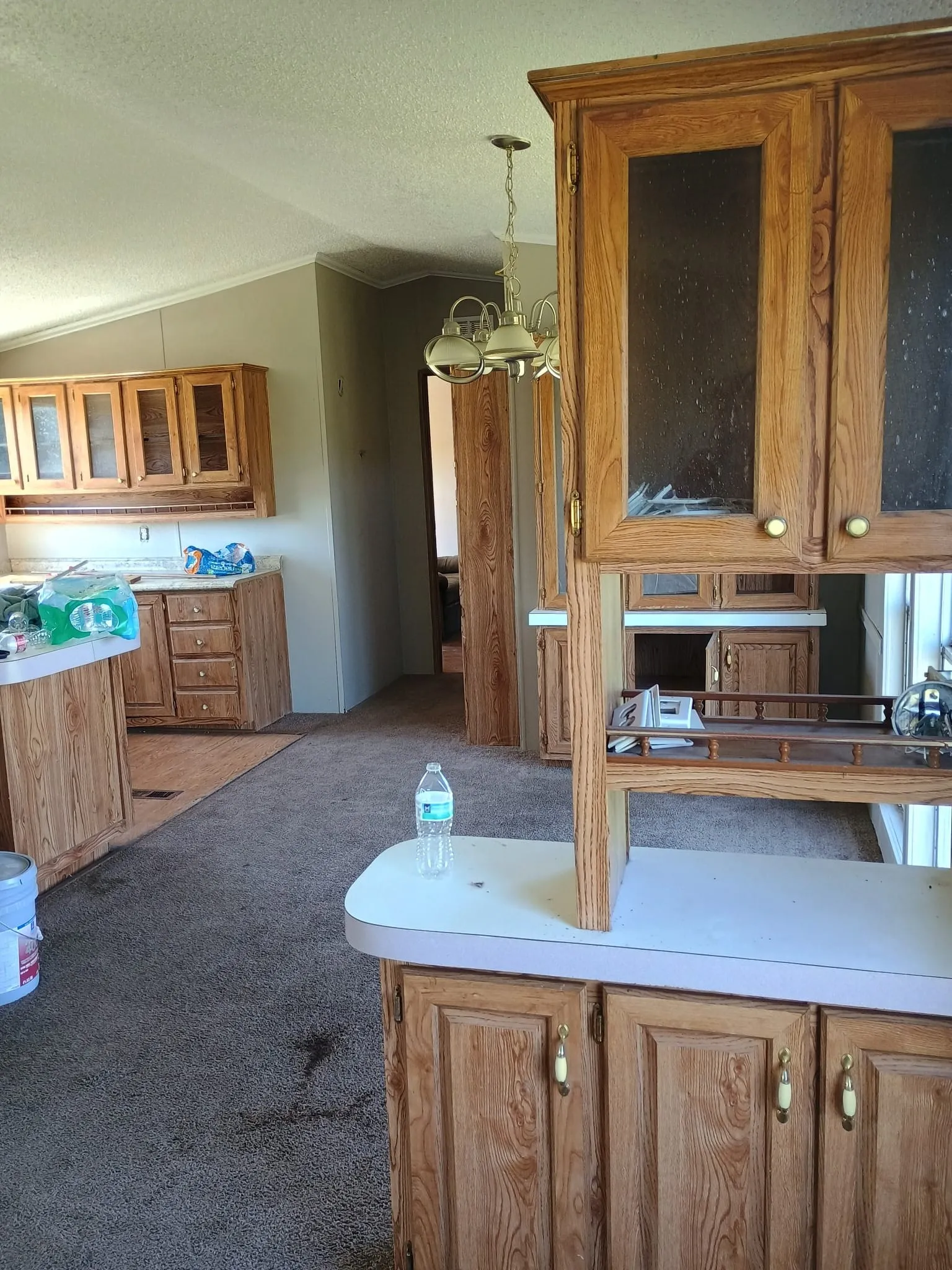 Kitchen featuring wood cabinetry with glass-front uppers and white laminate countertops