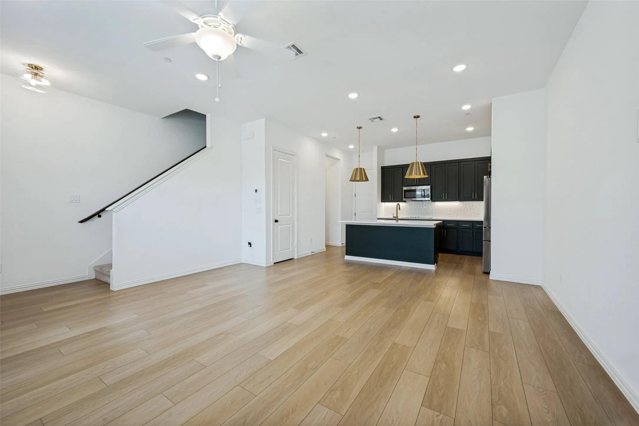 Open-concept living space featuring warm wood-finish flooring throughout, white walls, and ceiling-mounted lighting