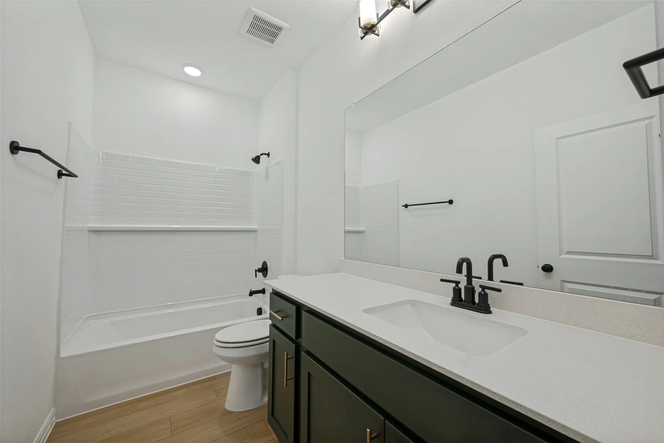 Spa-inspired primary bathroom featuring a dark vanity with dual-sink configuration, white quartz countertop, and matte black fixtures