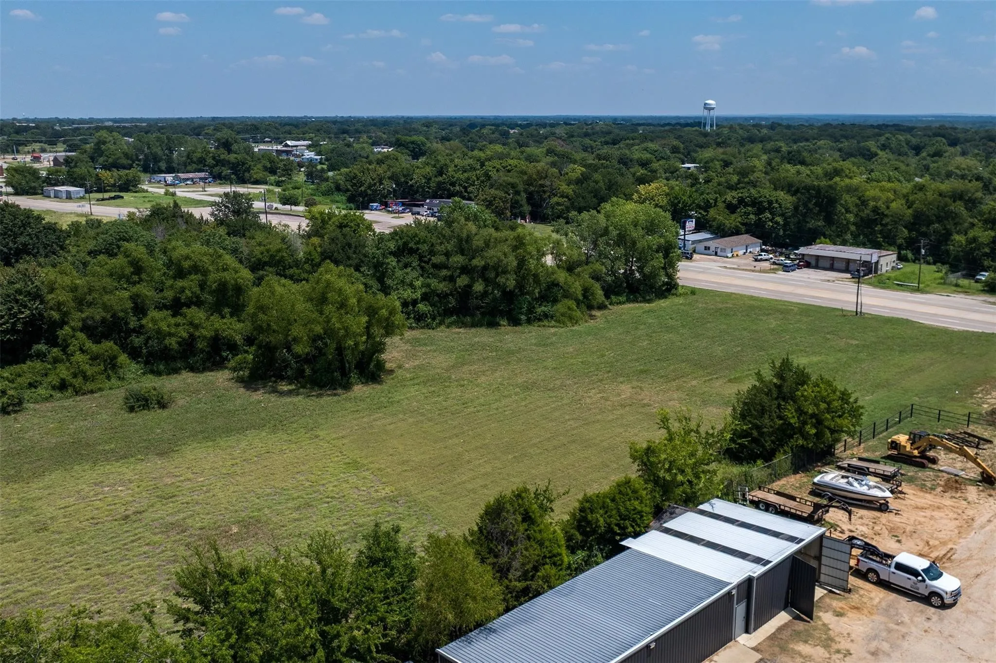 Expansive property featuring a large open field, perimeter fencing, and mature trees