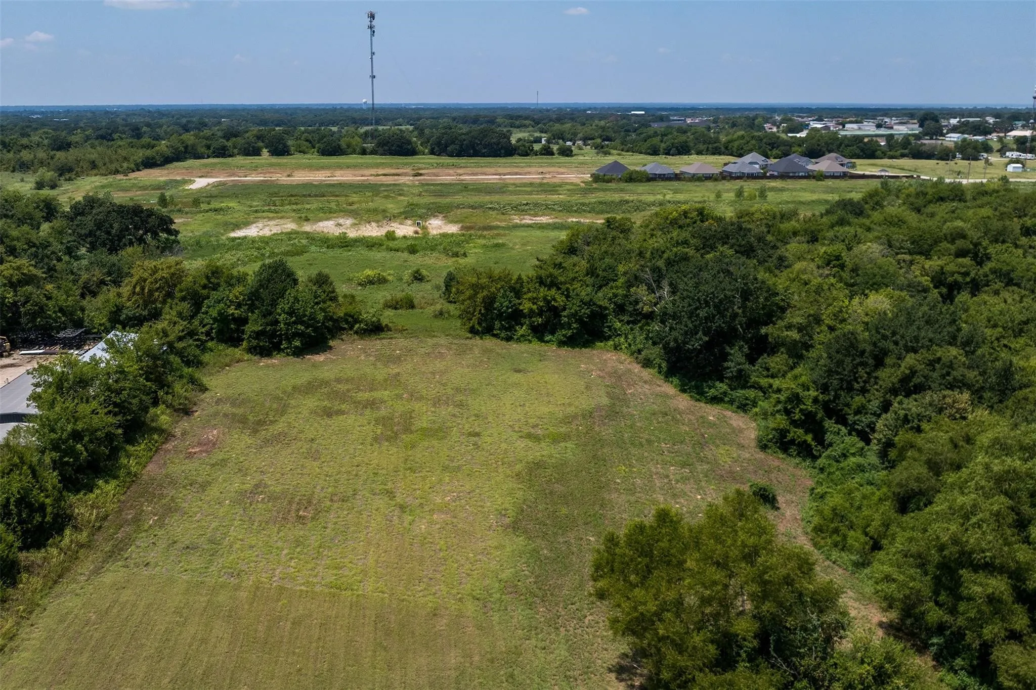 Expansive open land featuring a cleared, level parcel surrounded by mature trees and natural areas