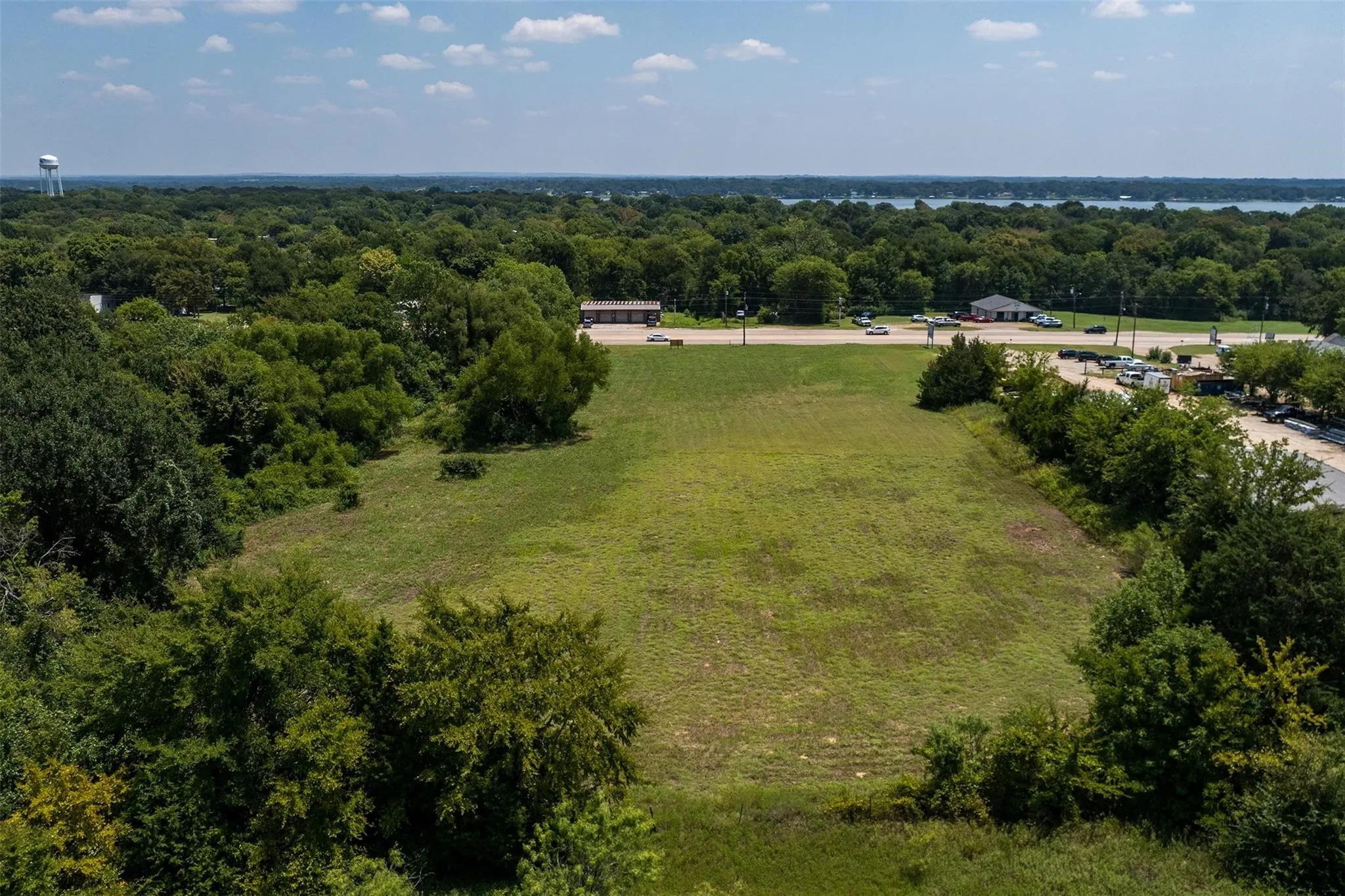 Expansive cleared lot surrounded by mature trees, featuring a flat, open topography