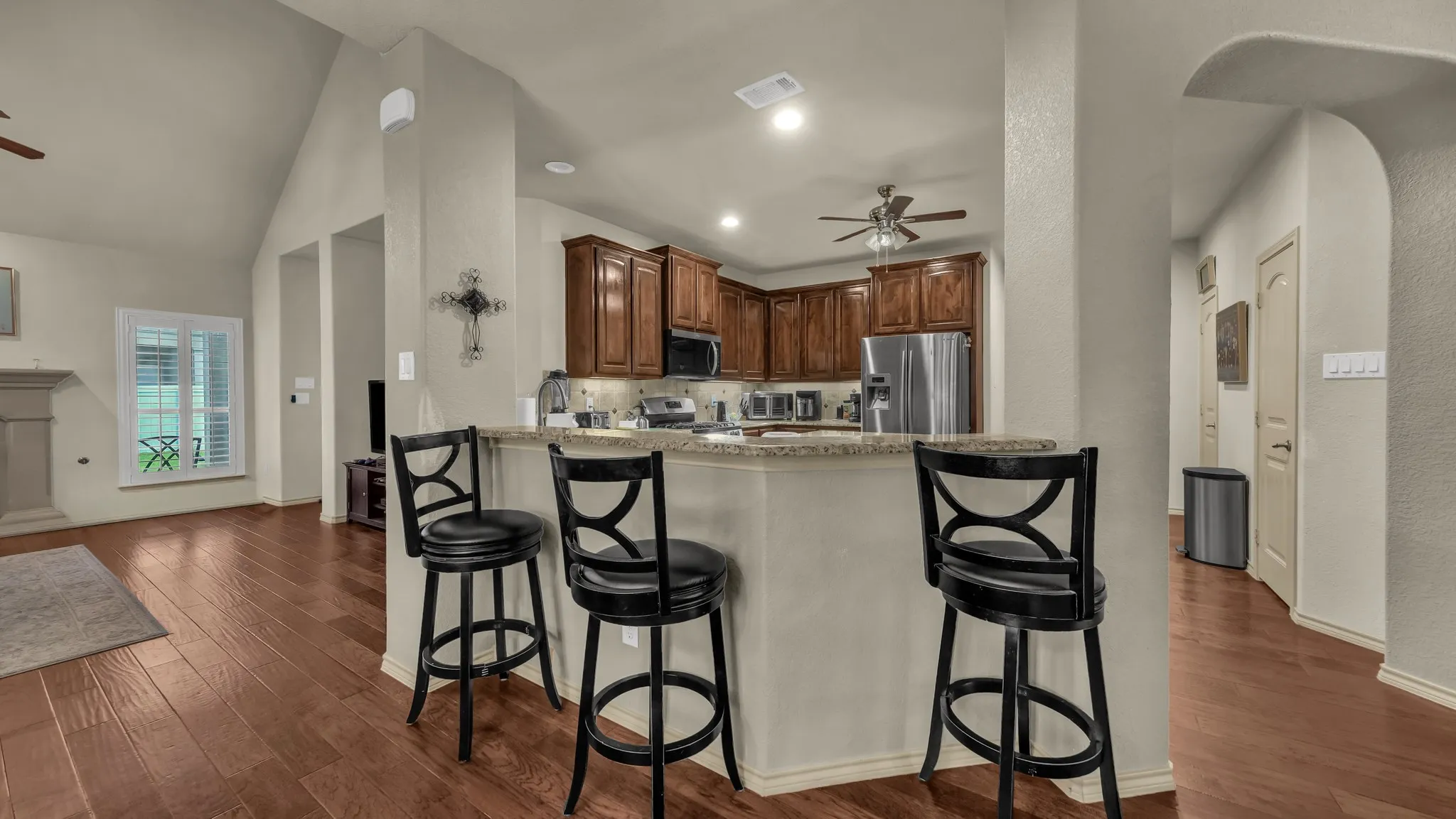 Kitchen with wood-finish cabinetry, stainless steel appliances, and a granite countertop breakfast bar with seating