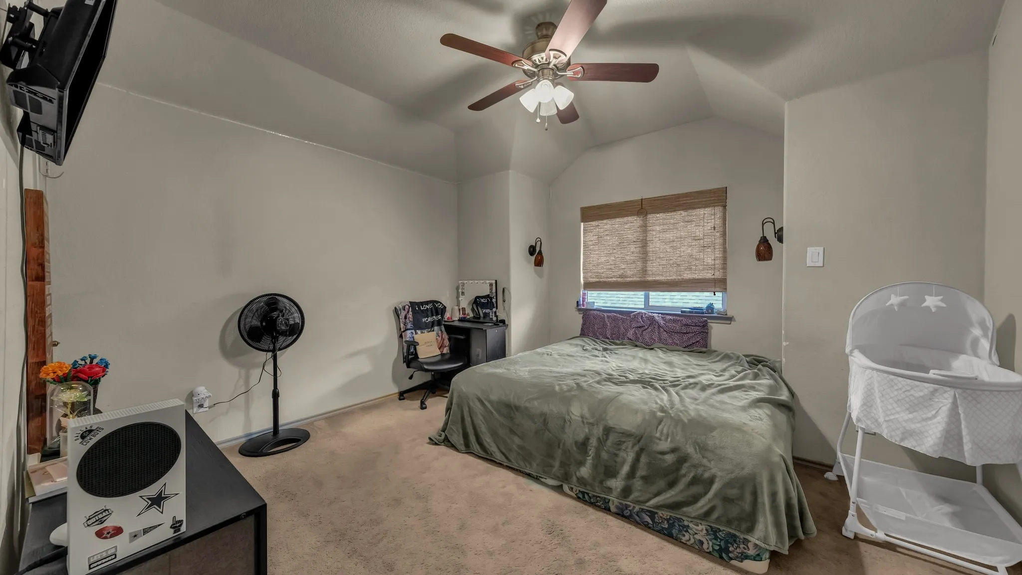 Carpeted room featuring a ceiling fan with light kit, sloped ceiling, and a window with a woven shade