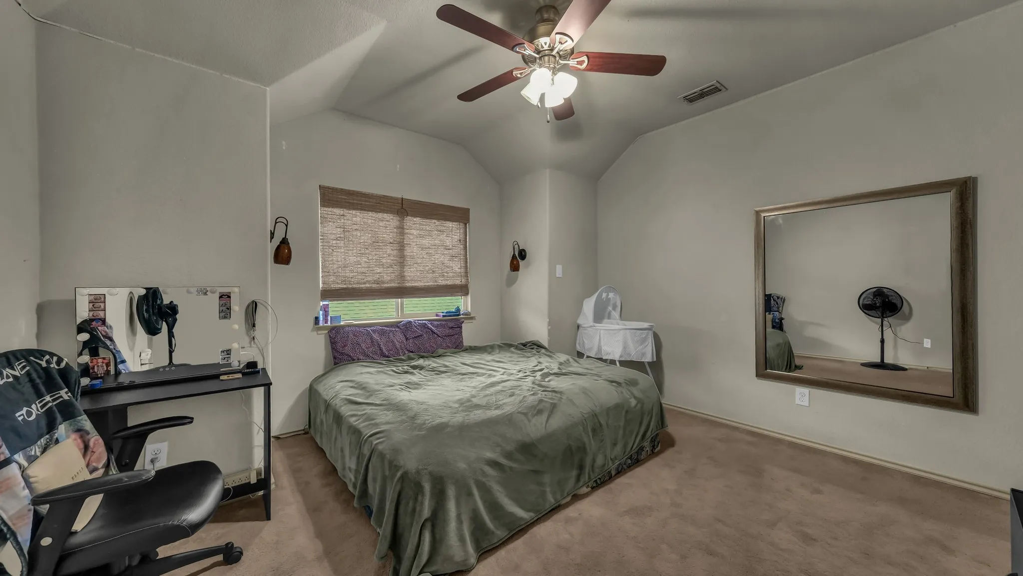 Carpeted room featuring a ceiling fan with integrated lighting, a window with woven blinds, and built-in wall sconces