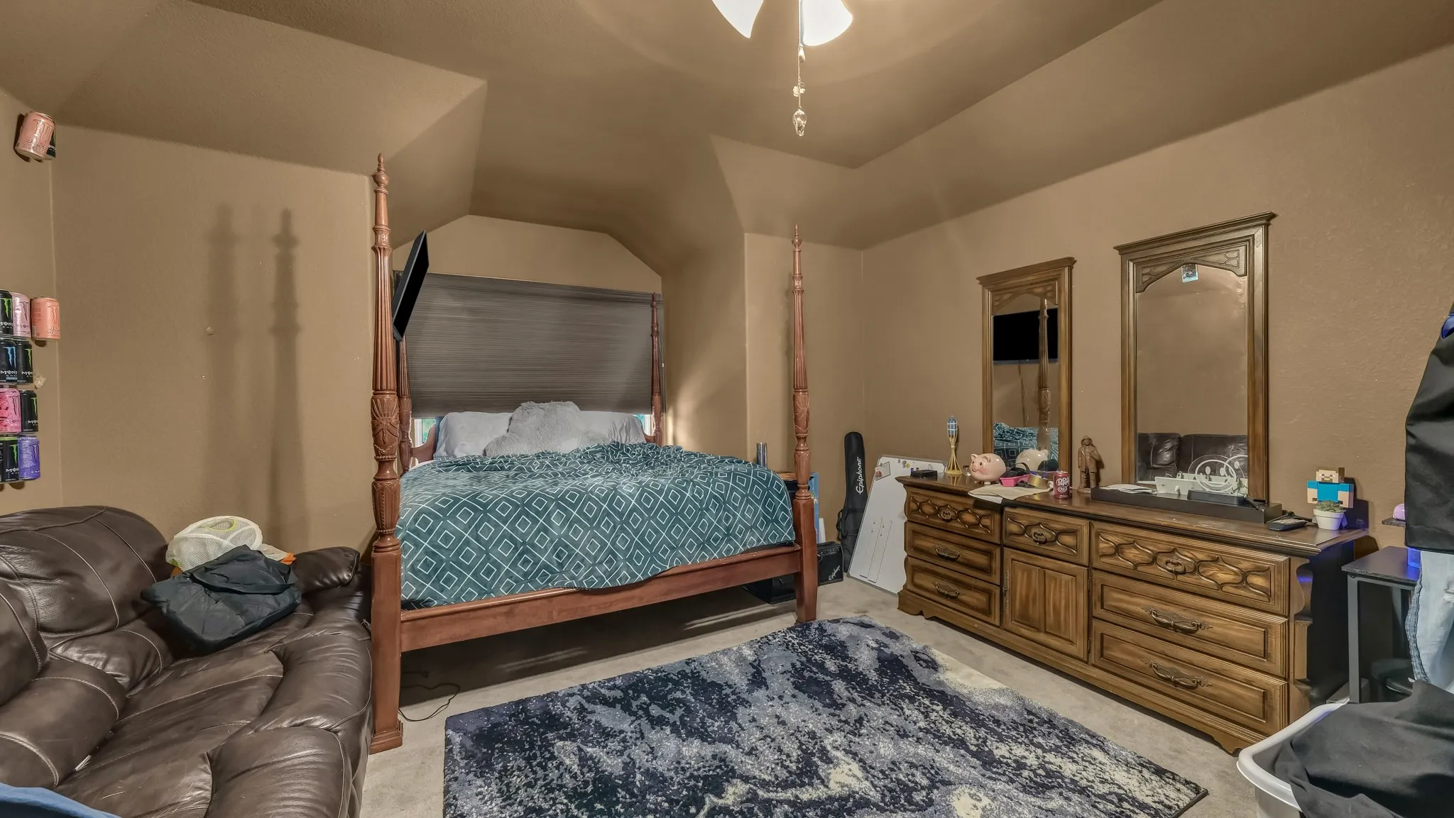 Bedroom featuring a vaulted ceiling and window with a roller shade