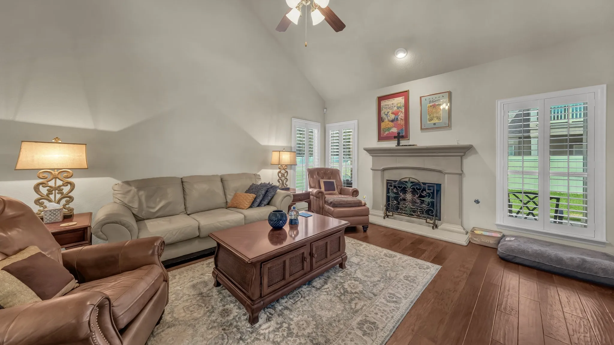 Living area featuring vaulted ceilings, wood-finish flooring, and a stately fireplace with a decorative mantel