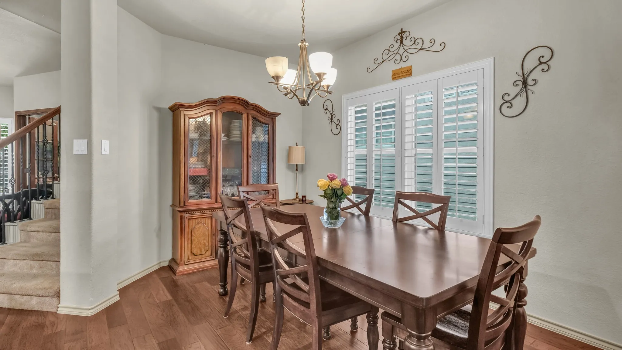 Dining area featuring wood-finish flooring, a multi-light chandelier, and a window with white plantation shutters