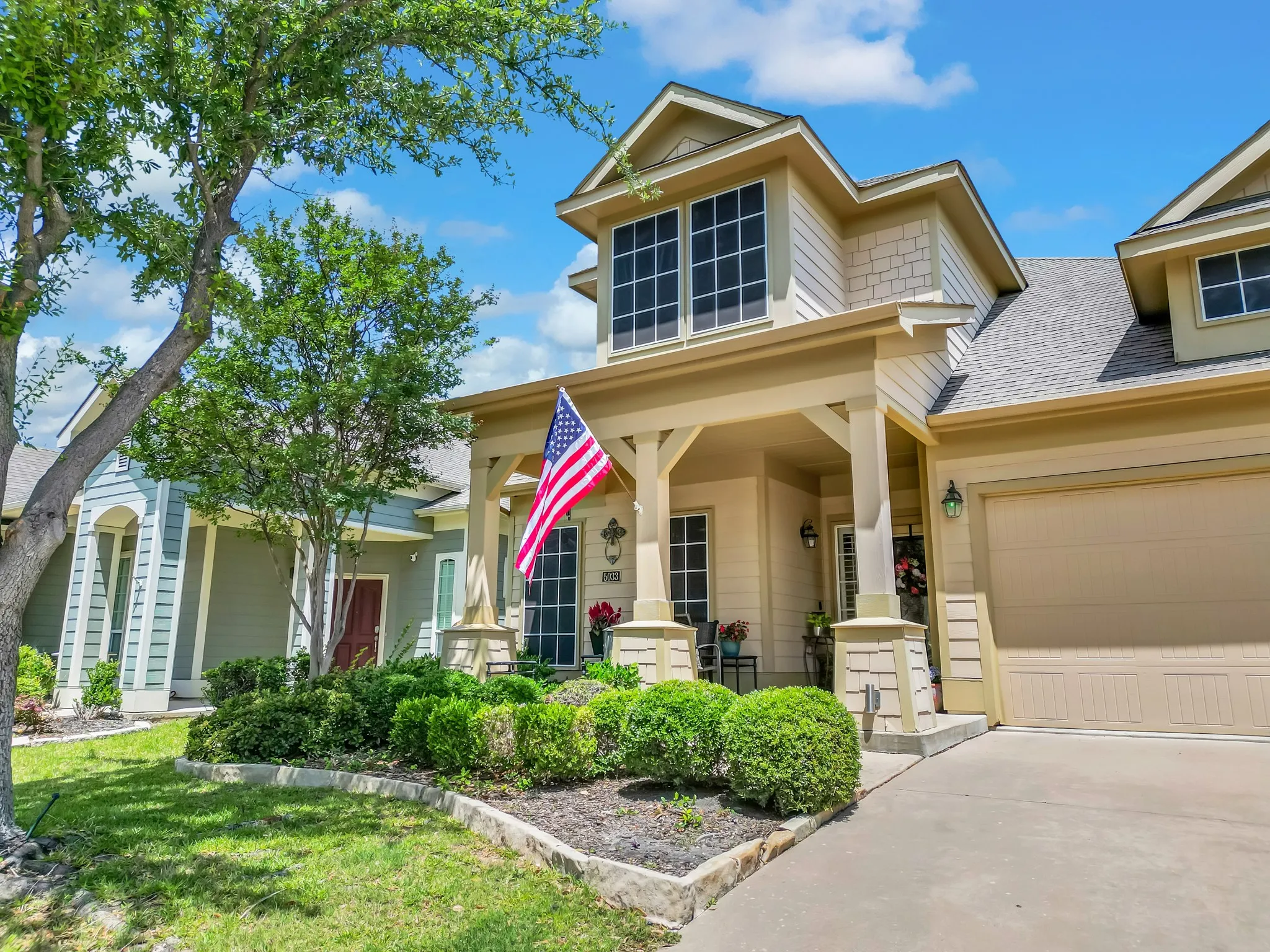 Two-story residence featuring a covered front porch with substantial columns, a two-car garage, and dormer windows