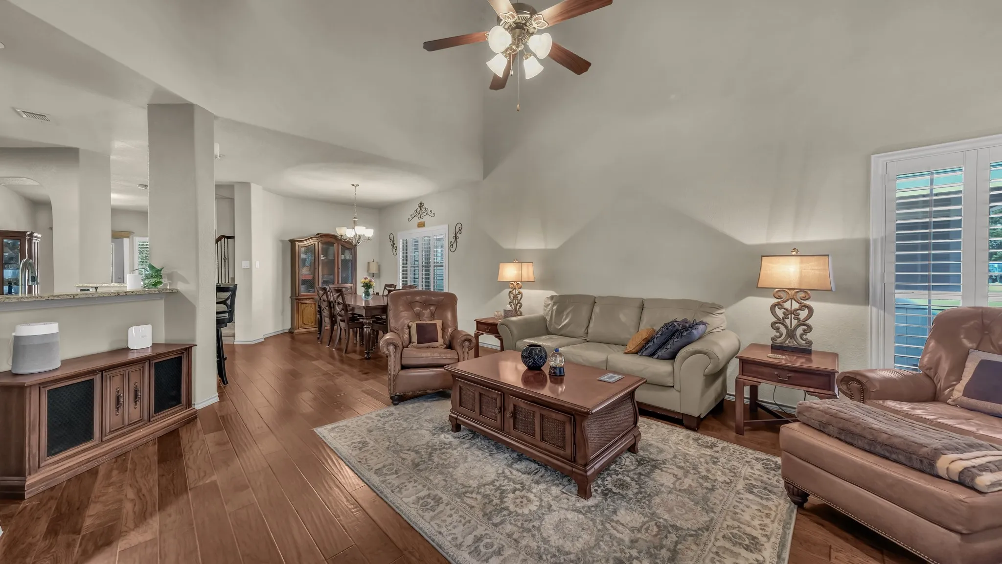 Vaulted ceilings enhance this living area featuring wood-finish flooring and neutral wall tones