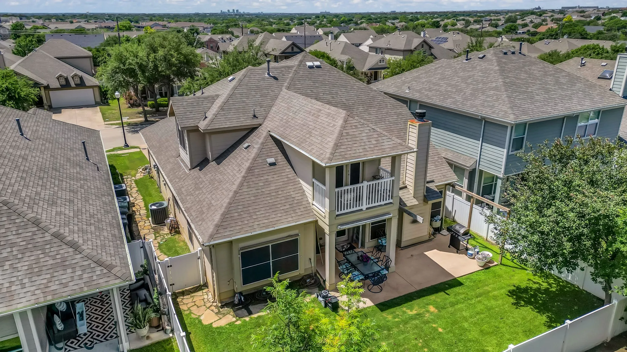Rear exterior featuring a covered patio, second-story balcony, and a fenced lawn area