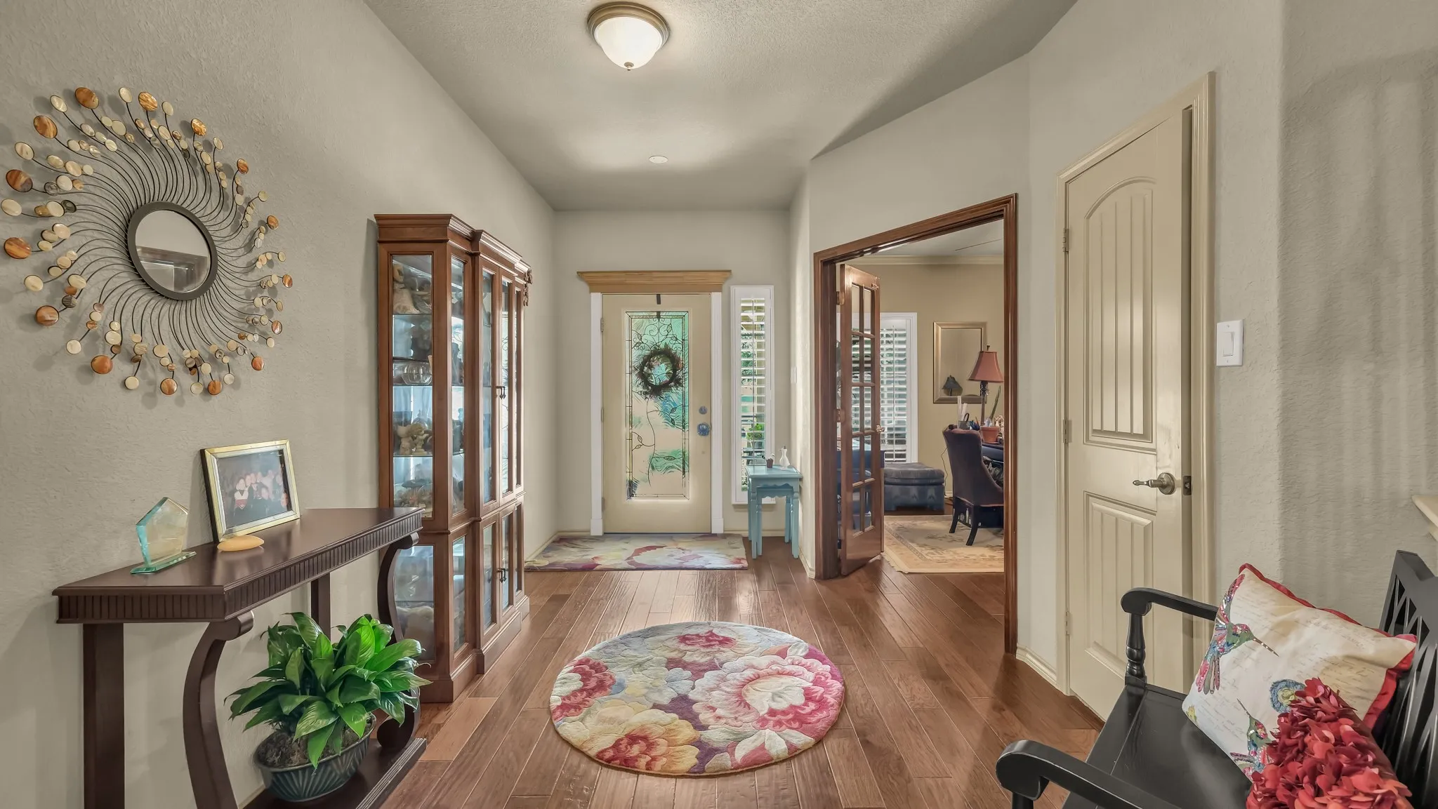 Entryway featuring wood-finish flooring, a decorative front door with transom window, and an arched doorway with French doors