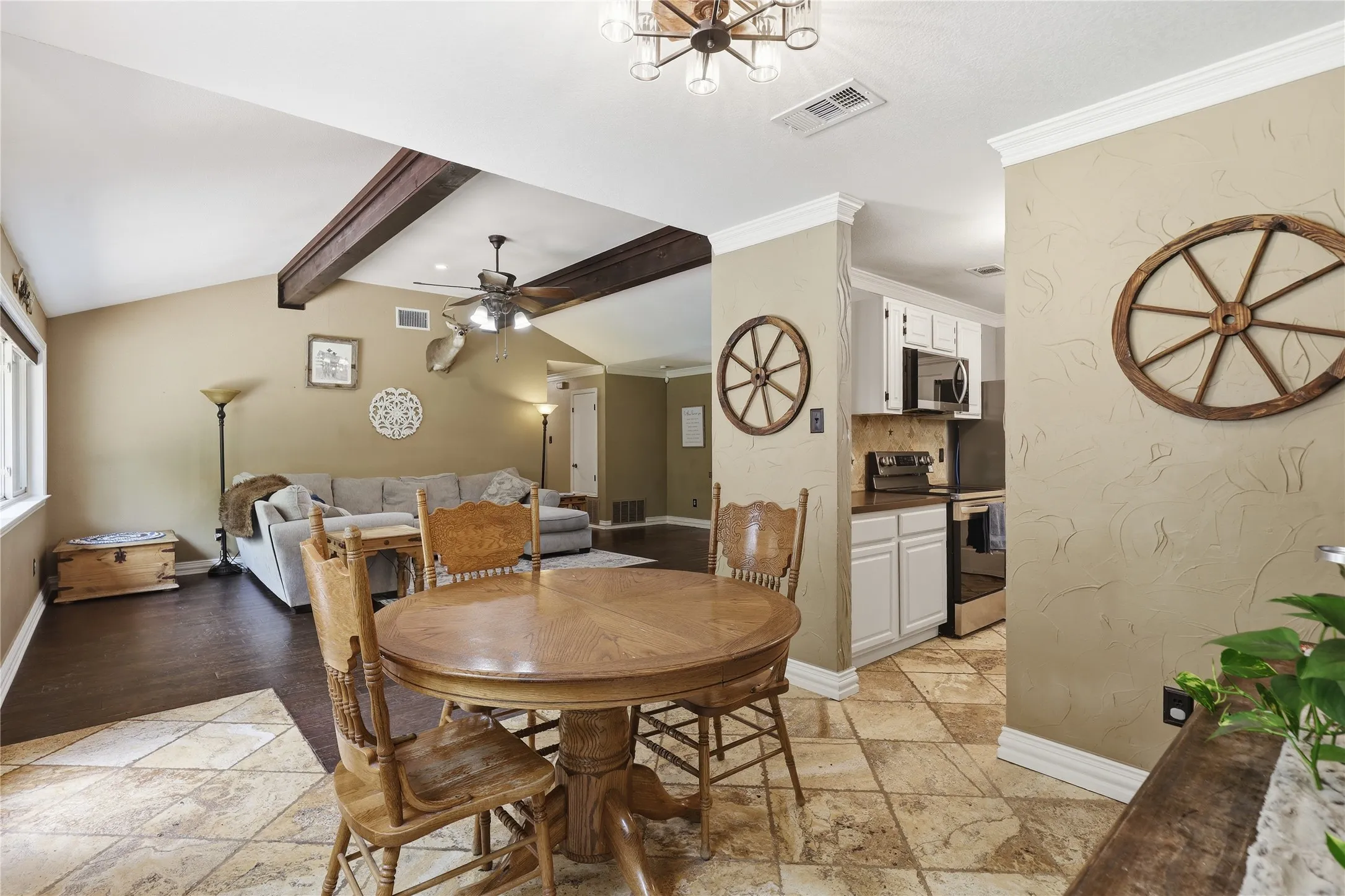 Open-concept living space featuring vaulted ceilings with exposed beams, wood-finish flooring, and a ceiling fan