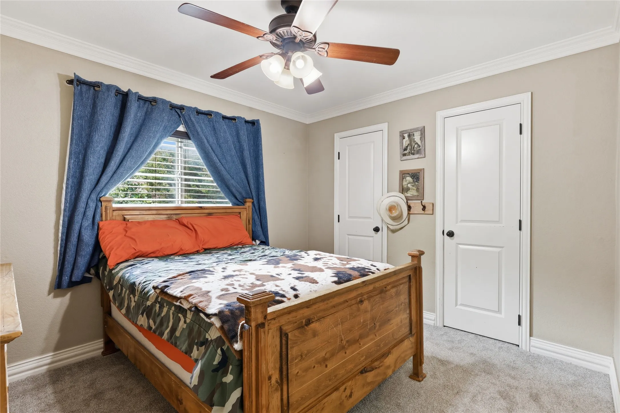 Carpeted room featuring a ceiling fan with integrated lighting, crown molding, white baseboards, and two paneled interior doors