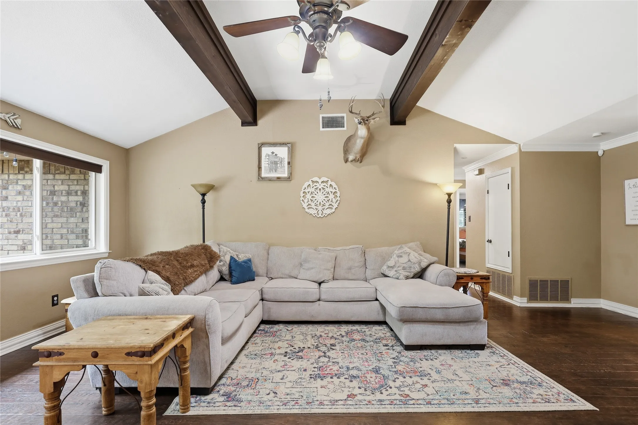 Living area featuring vaulted ceilings with exposed wood beams, a ceiling fan, and wood-finish flooring