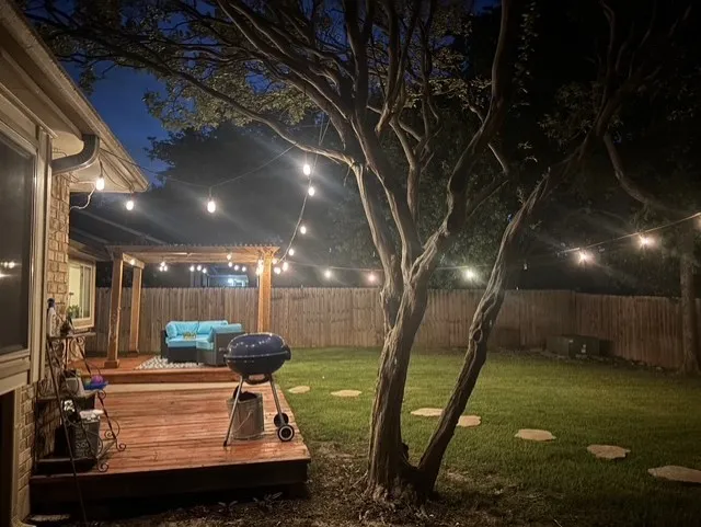 Expansive backyard featuring a multi-level wood deck, a covered pergola, a manicured lawn, stone step pathways, and wood privacy fencing